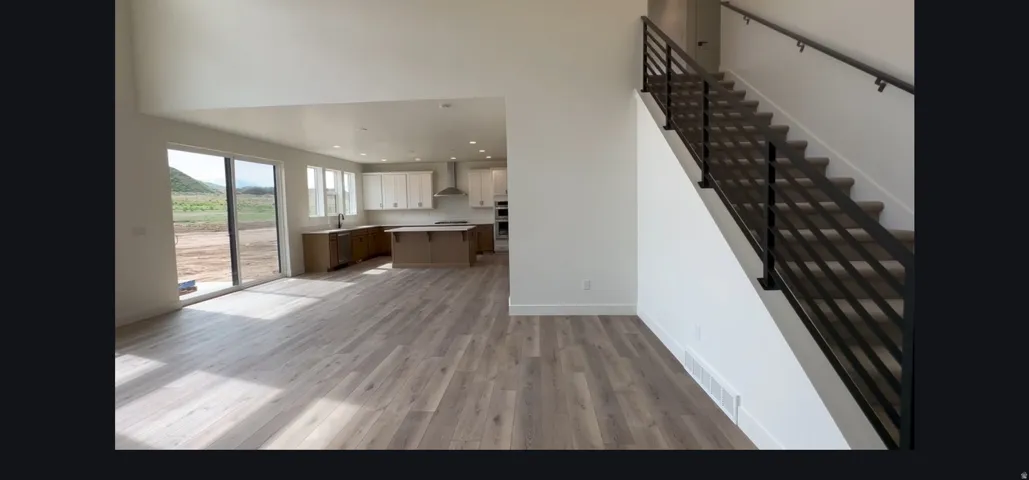 Open concept living area featuring wood-finish flooring and a contemporary staircase with black metal railings