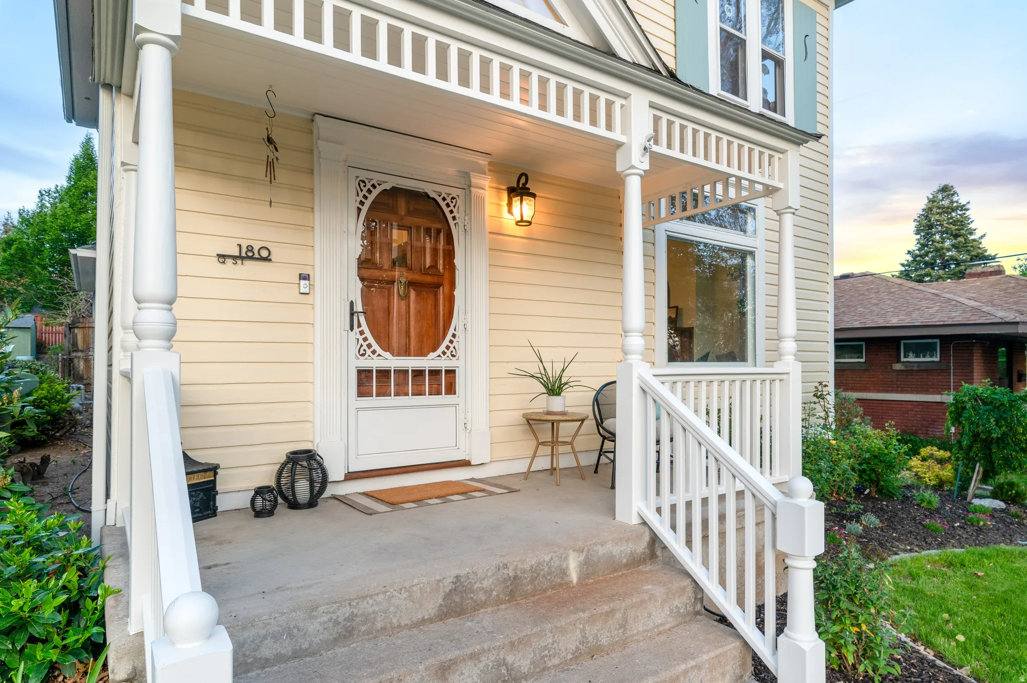 Inviting front porch featuring a decorative wood entry door, white railings, and a wall-mounted light fixture
