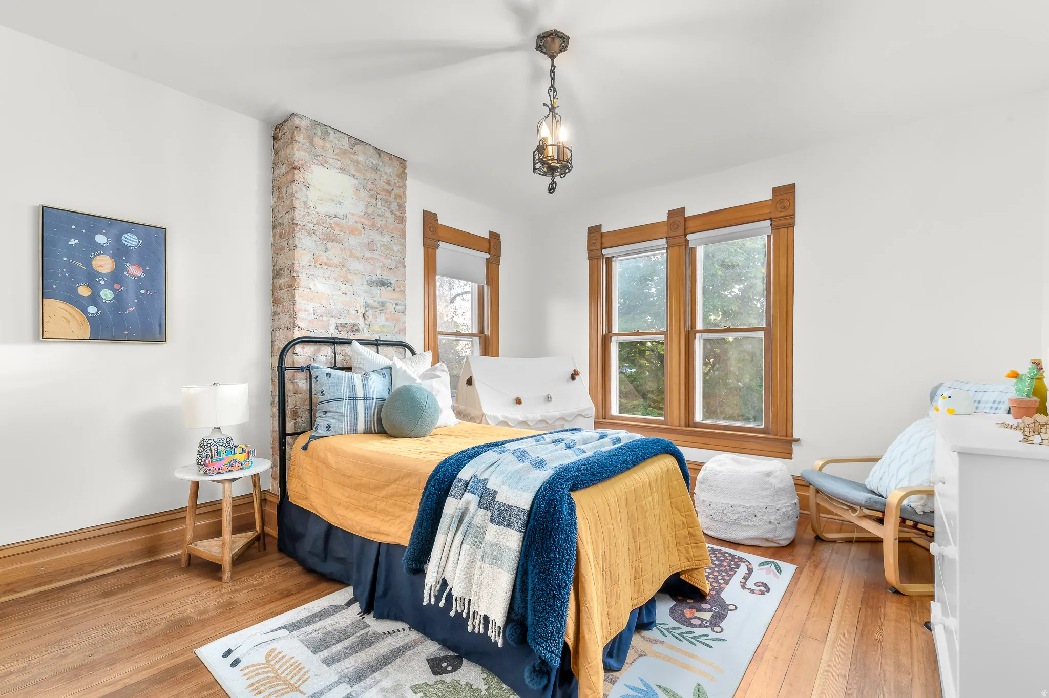 Bright room featuring wood-finish flooring, white walls, and a prominent exposed brick column