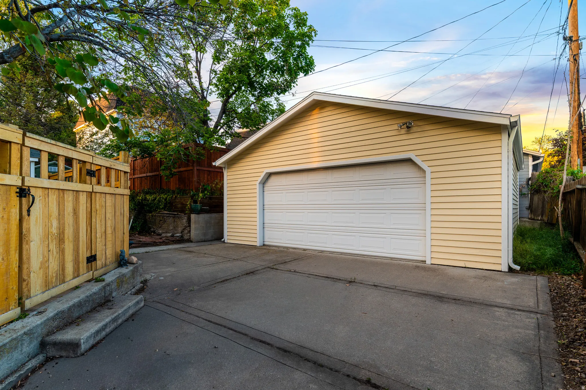 Detached two-car garage with light yellow siding and a white paneled garage door