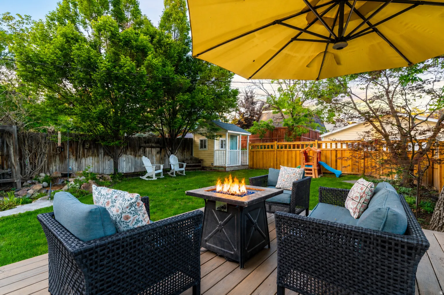 Expansive backyard featuring a composite deck, mature trees, a manicured lawn, and a wooden privacy fence