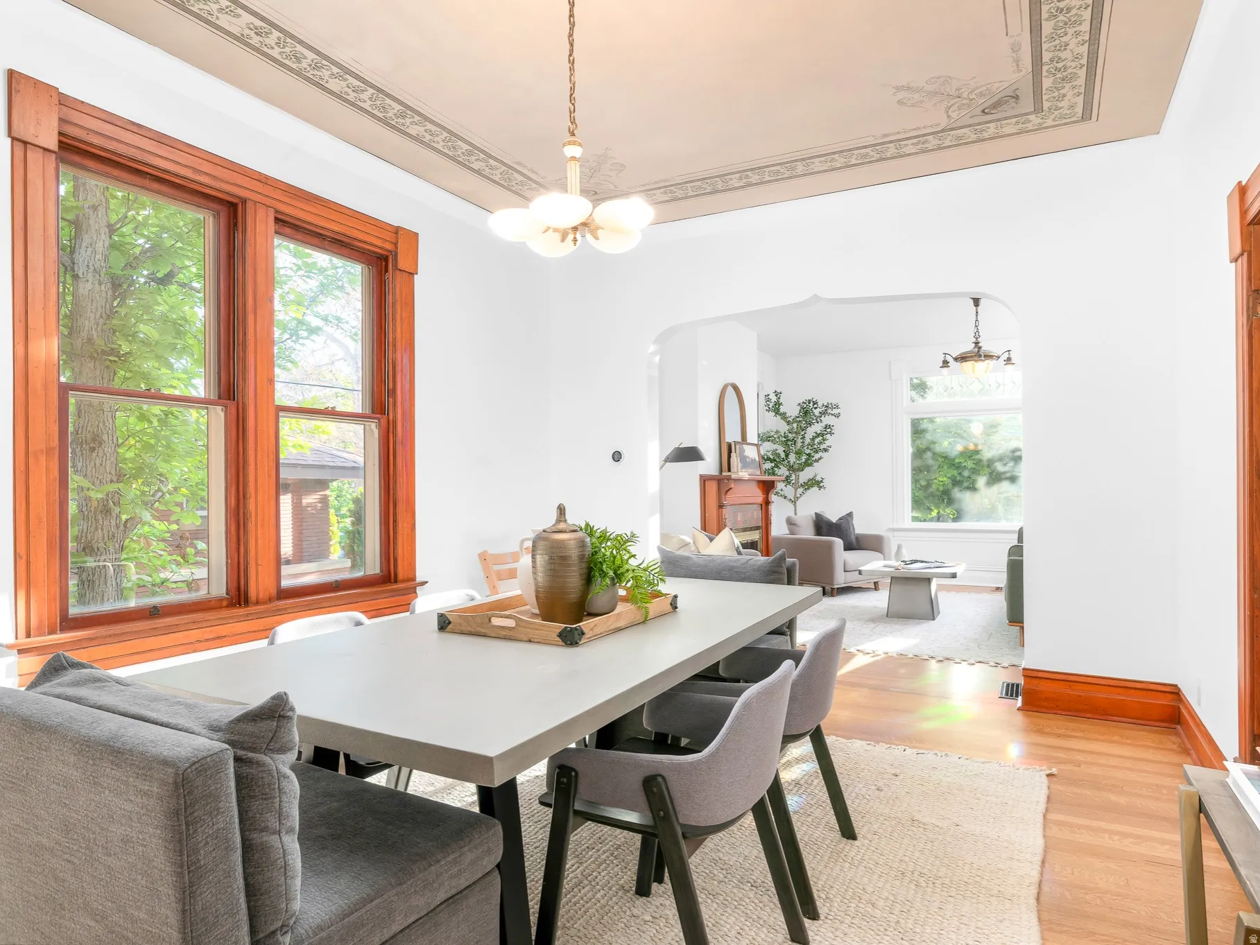 Dining area featuring hardwood flooring, detailed wood window trim, a decorative ceiling medallion, and an arched entryway