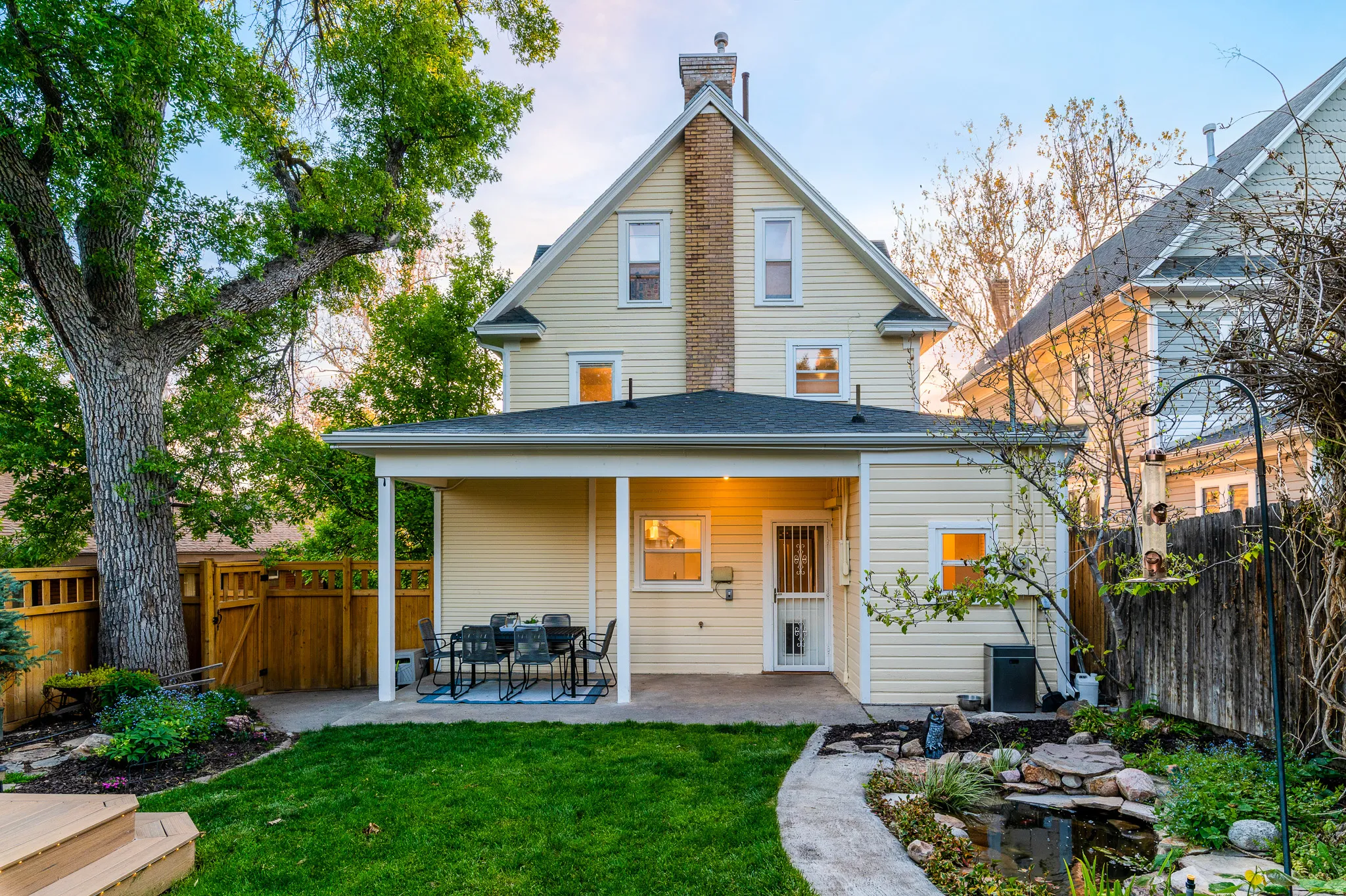 Rear exterior featuring a covered patio, manicured lawn, and a decorative pond