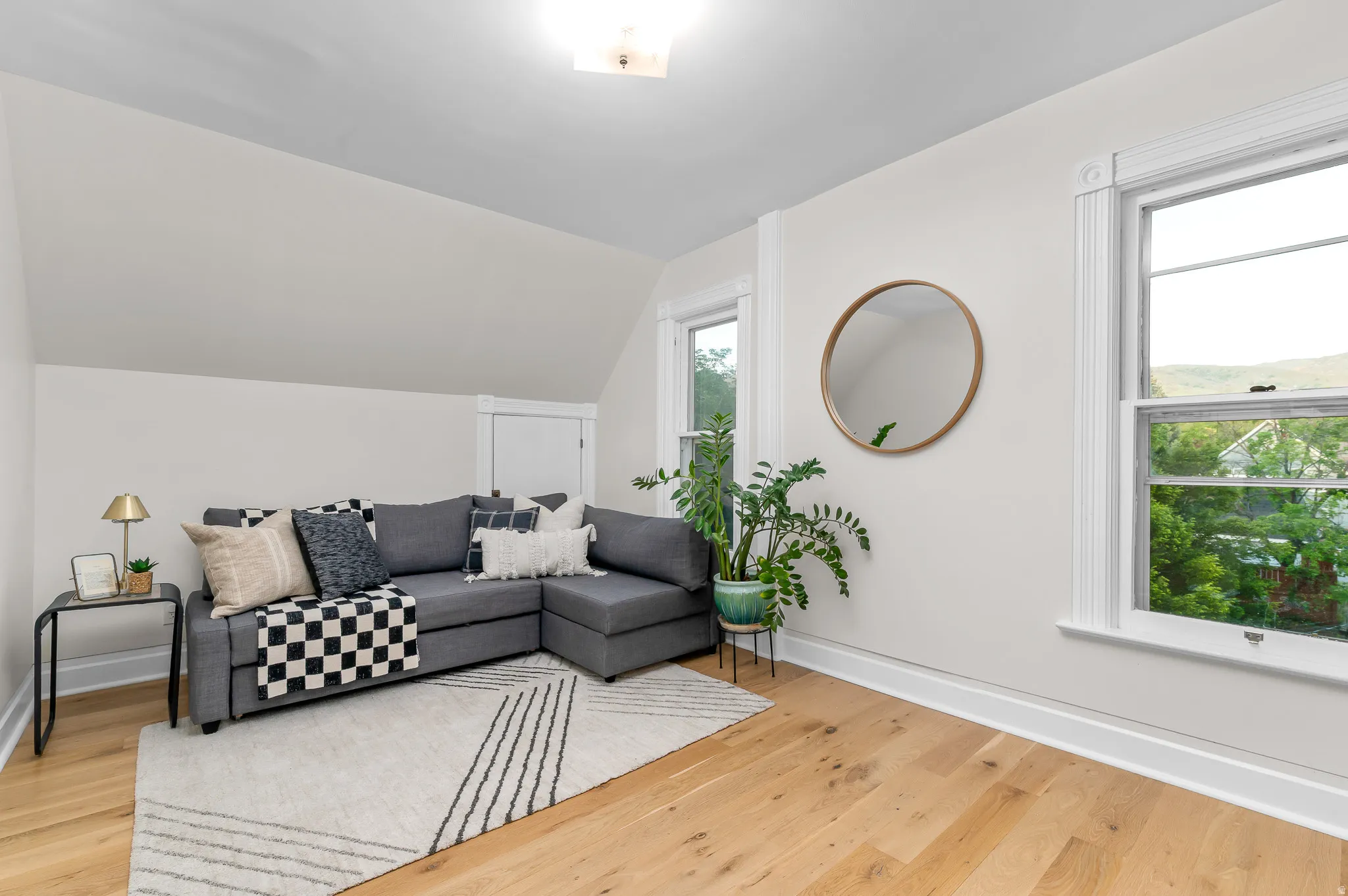 Bright room featuring light wood-finish flooring, white walls, and a sloped ceiling