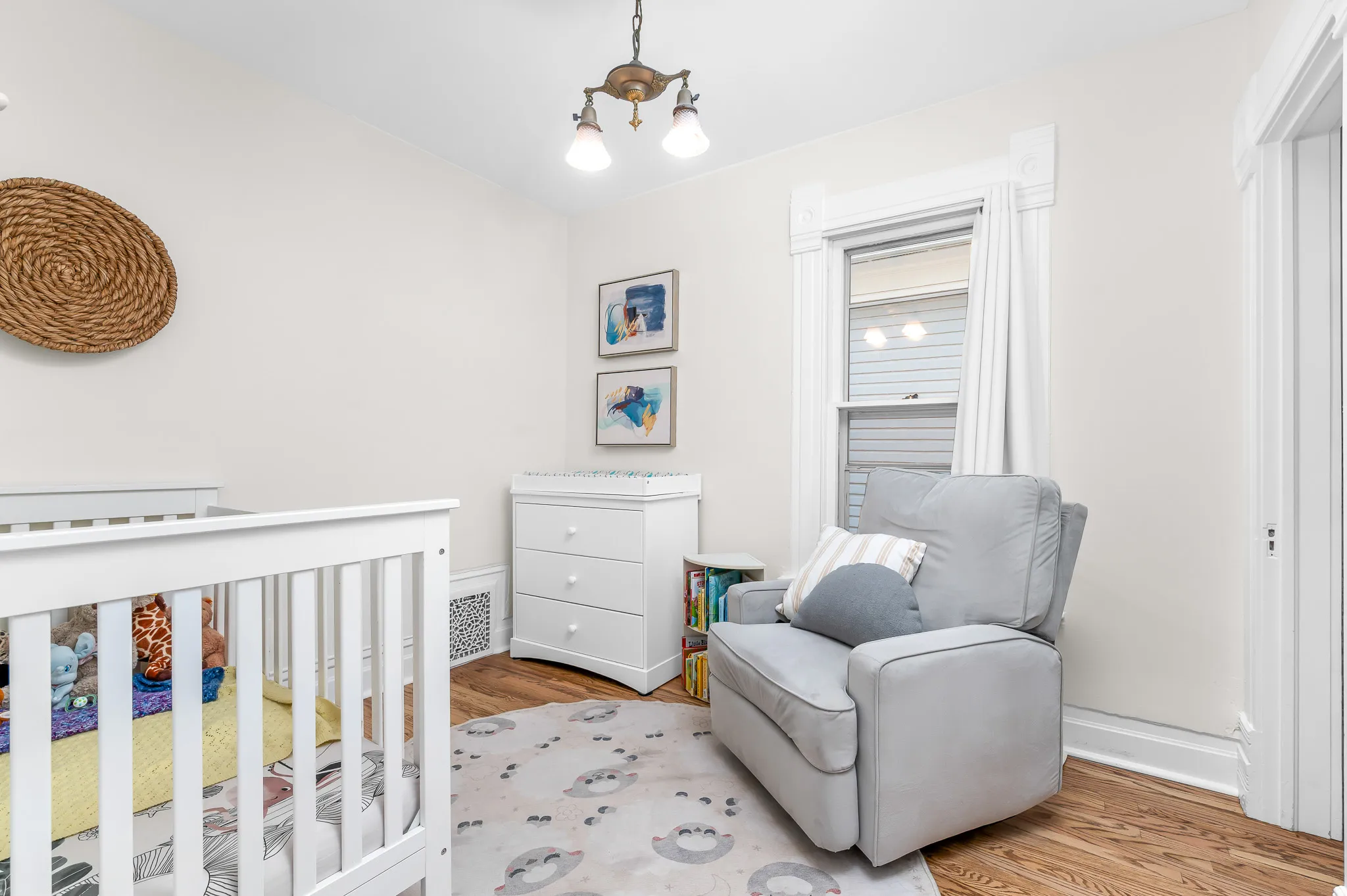 Room featuring wood-finish flooring, a window with detailed trim, and a classic-style ceiling light fixture