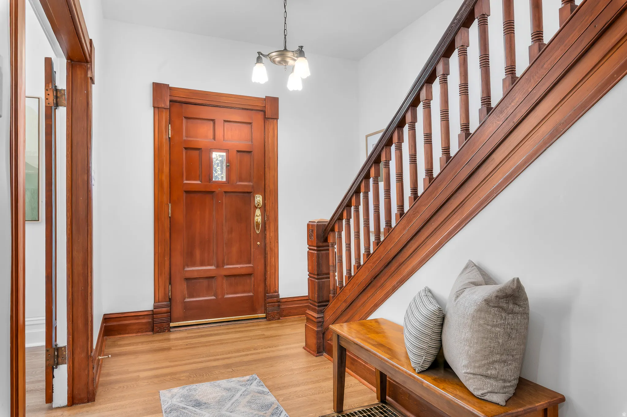 Entryway featuring a paneled wood door with decorative glass insert, rich wood-finish trim, and a full wood staircase with balusters