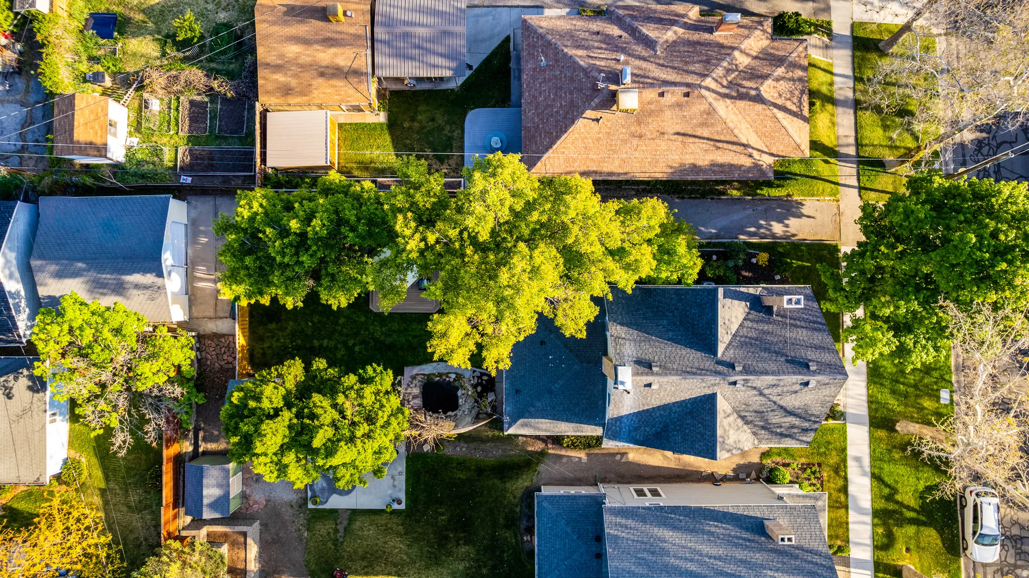 Aerial perspective showcasing a residential neighborhood with varied roofing styles, green landscaping, and street infrastructure