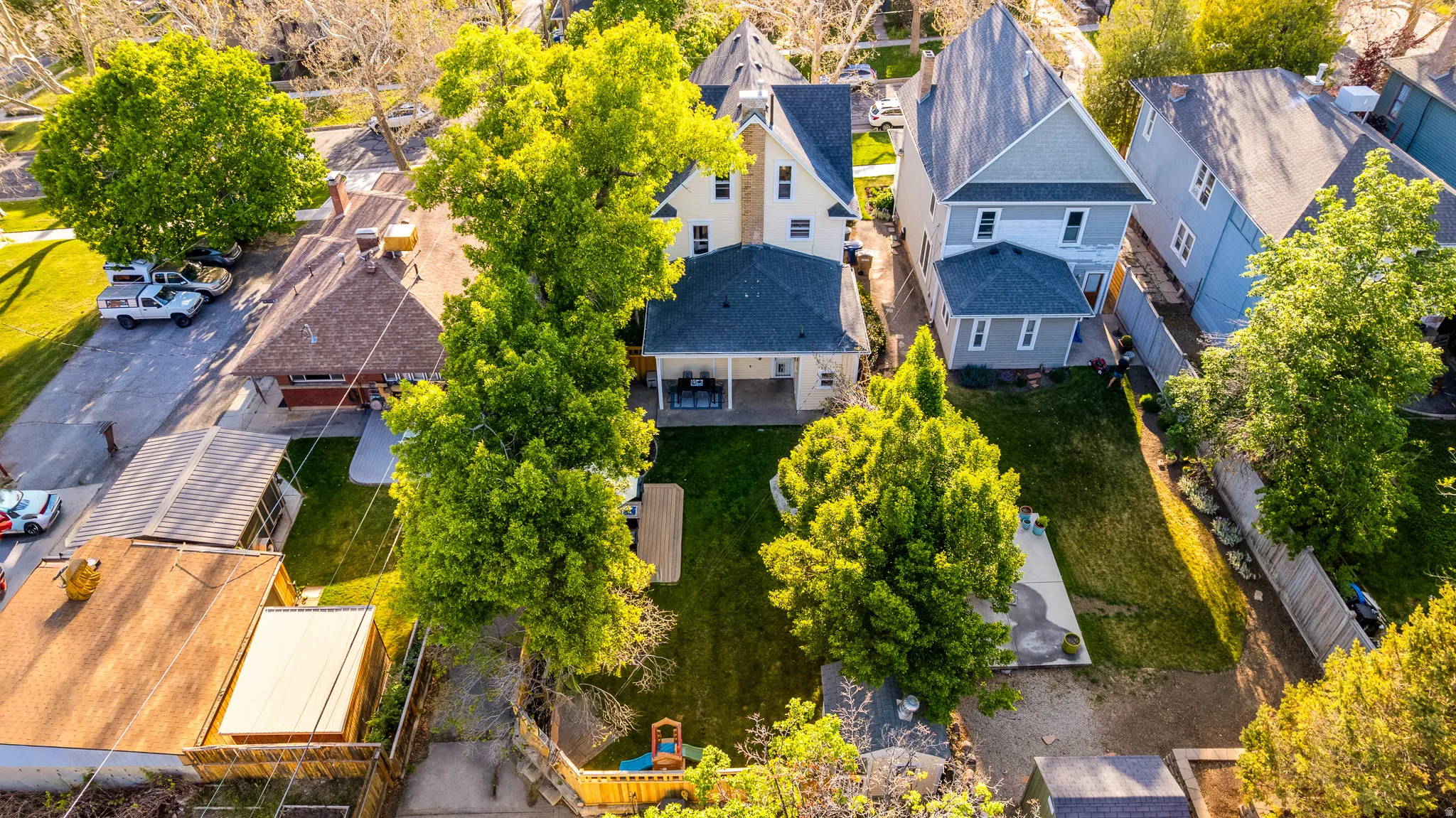 Expansive backyard featuring a manicured lawn, mature trees, and a wooden fence