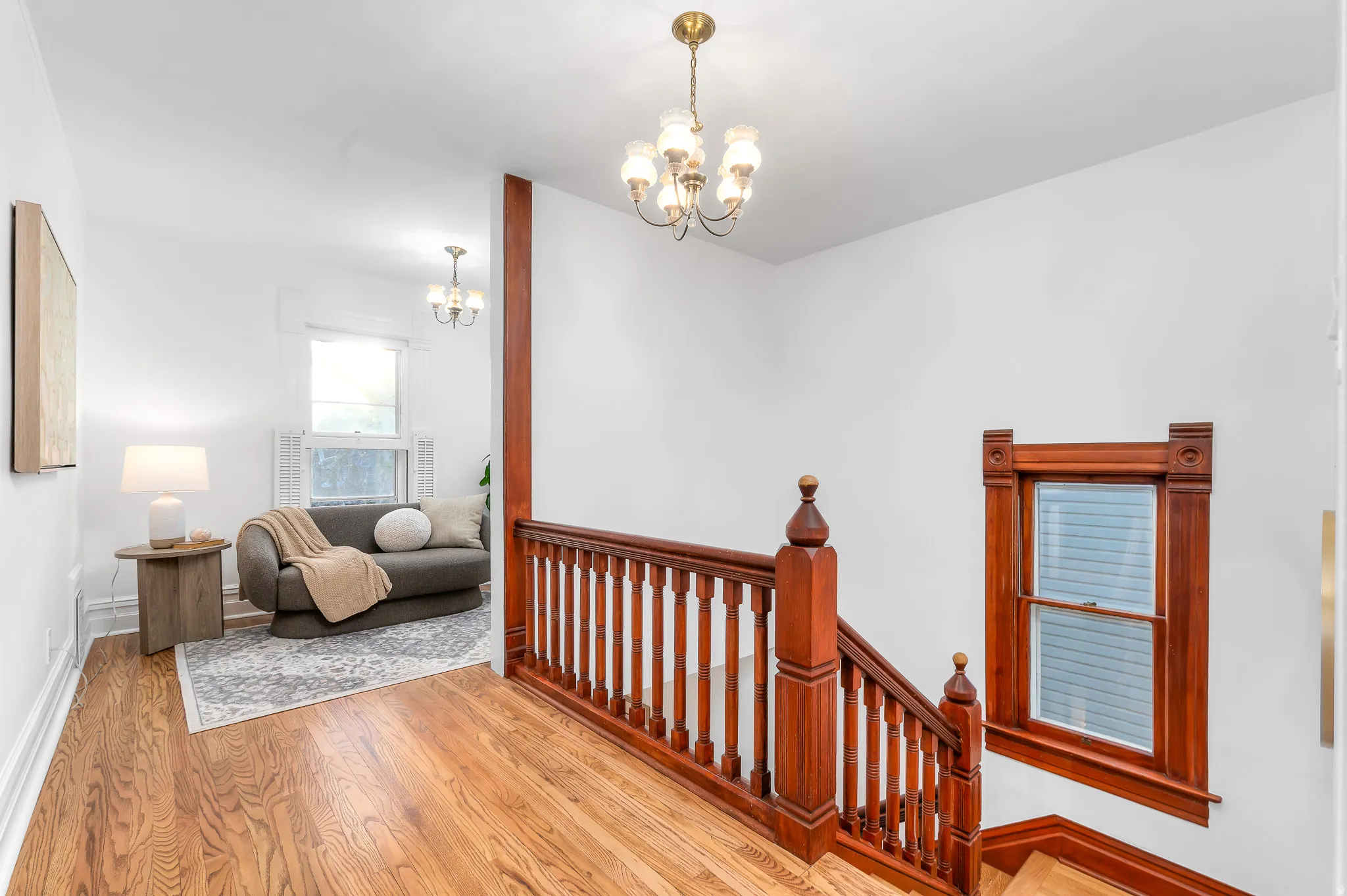 Hardwood flooring extends throughout this upper level, complementing the stained wood staircase and custom window trim