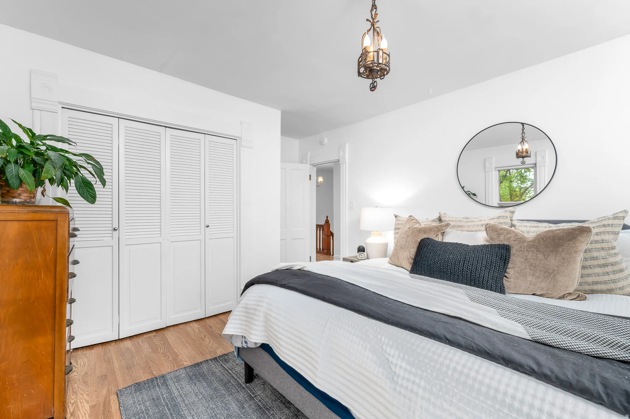 Bedroom with wood-finish flooring, white walls, and louvered bi-fold closet doors