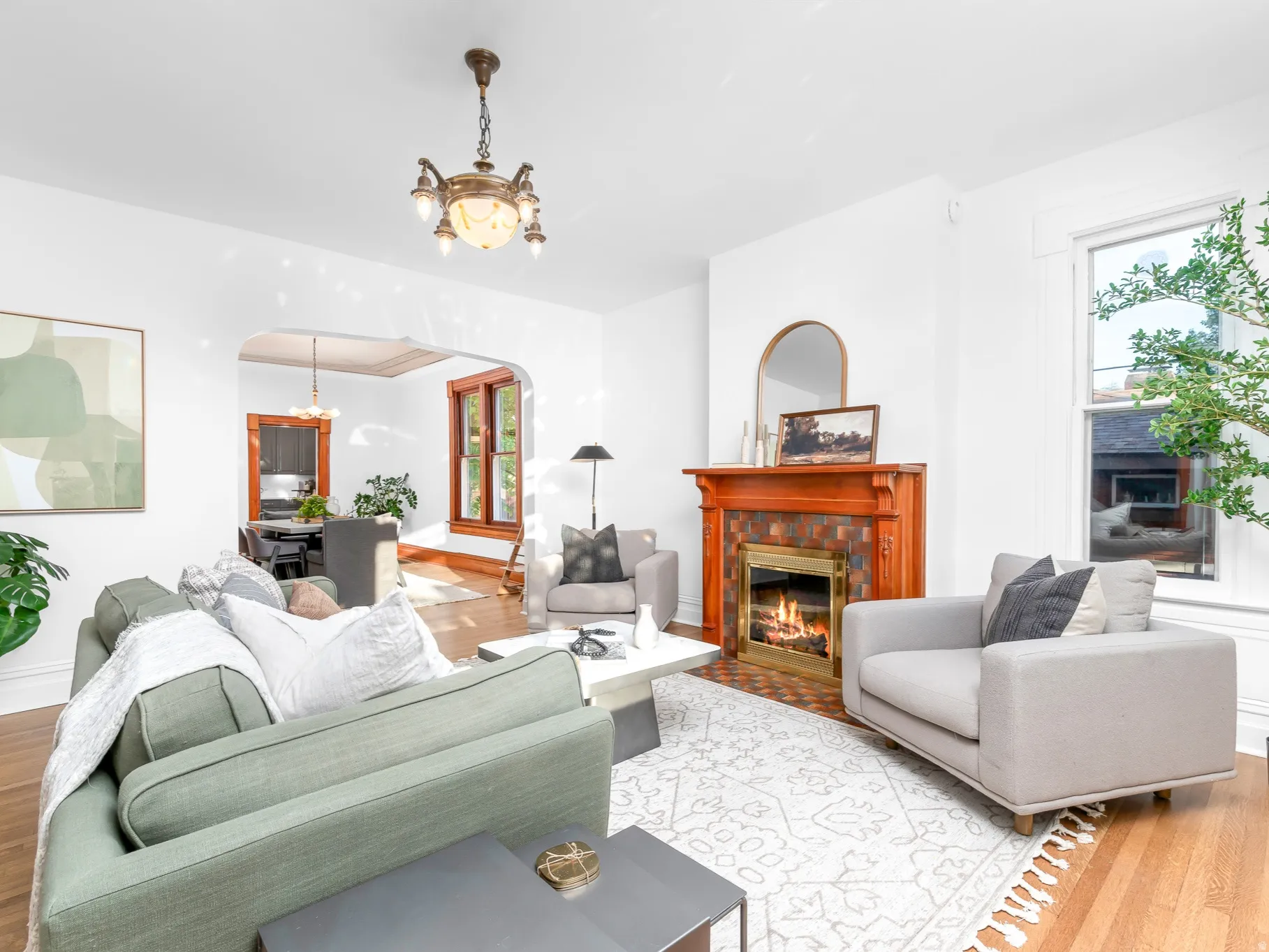 Living area featuring a traditional wood mantel fireplace with tile surround, hardwood flooring, and an arched doorway