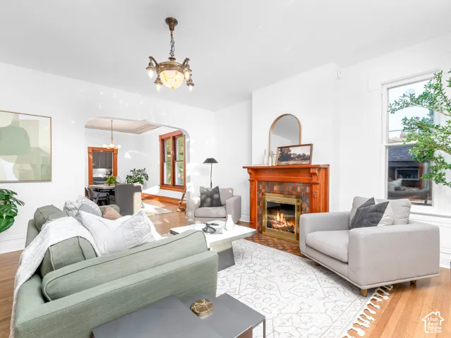 Living area featuring a traditional wood mantel fireplace with tile surround, hardwood flooring, and an arched doorway