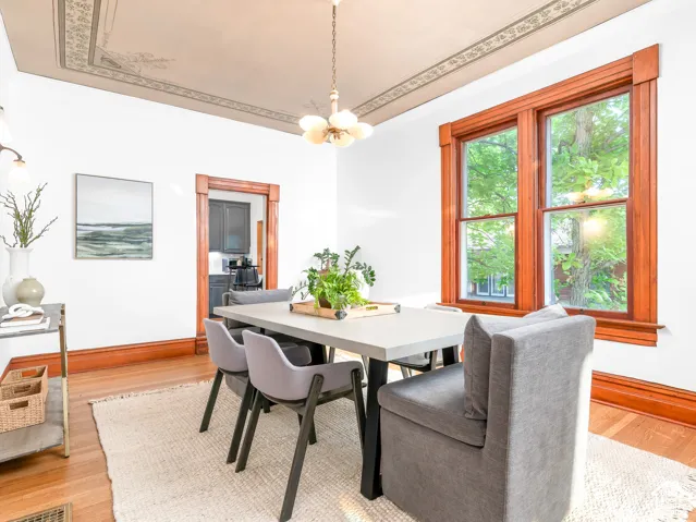 Dining space featuring wood-finish flooring, a decorative ceiling border, a light fixture, and a window with wood trim