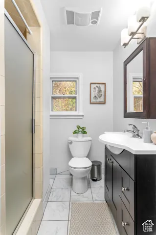 Bathroom featuring a white toilet, a frosted glass shower enclosure, and a dark wood-finish vanity with an integrated sink