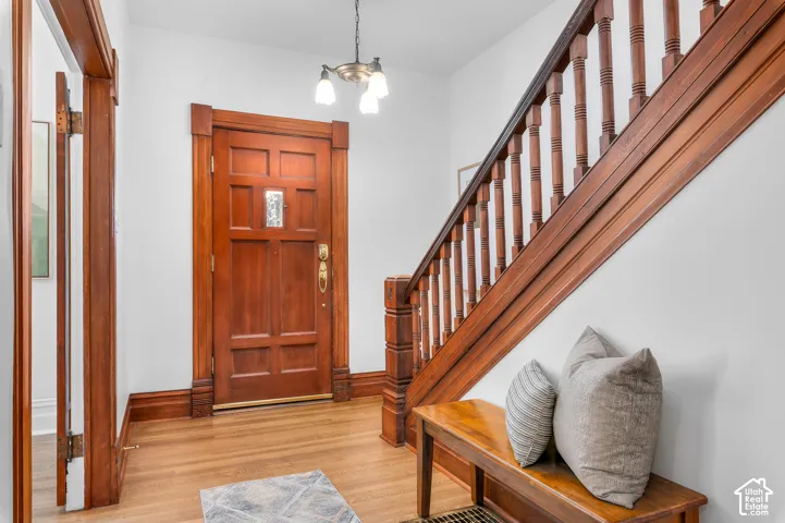 Entryway featuring a paneled wood door with decorative glass insert, rich wood-finish trim, and a full wood staircase with balusters