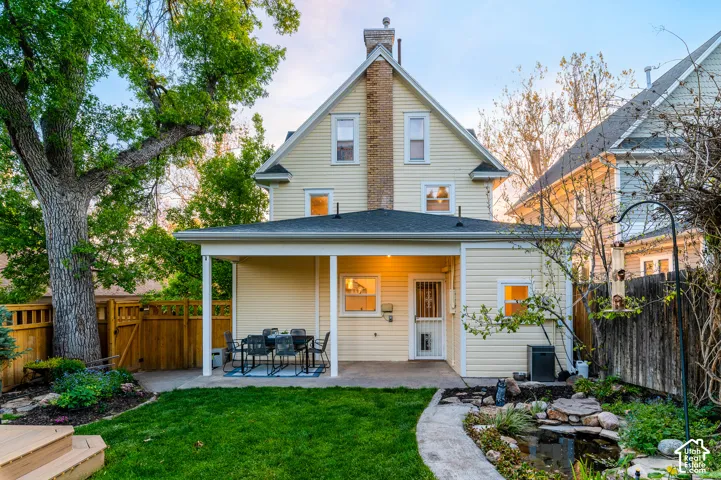 Rear exterior featuring a covered patio, manicured lawn, and a decorative pond