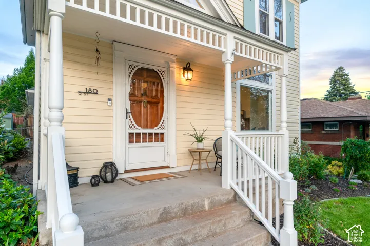 Inviting front porch featuring a decorative wood entry door, white railings, and a wall-mounted light fixture