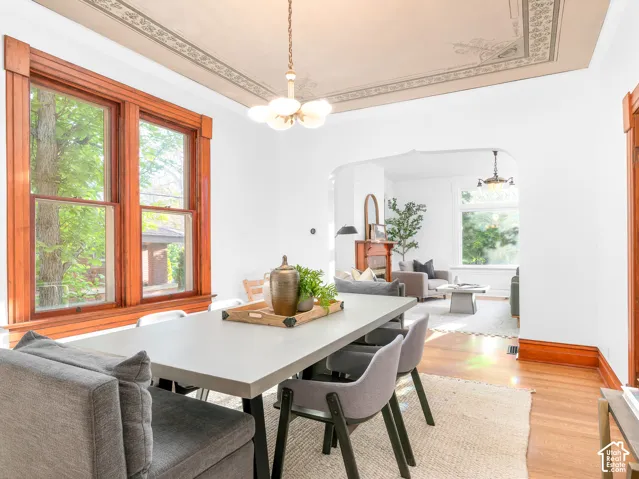 Dining area featuring hardwood flooring, detailed wood window trim, a decorative ceiling medallion, and an arched entryway