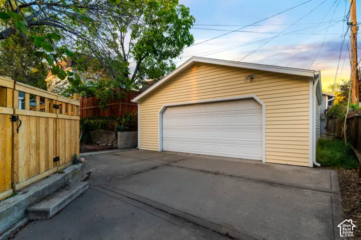 Detached two-car garage with light yellow siding and a white paneled garage door
