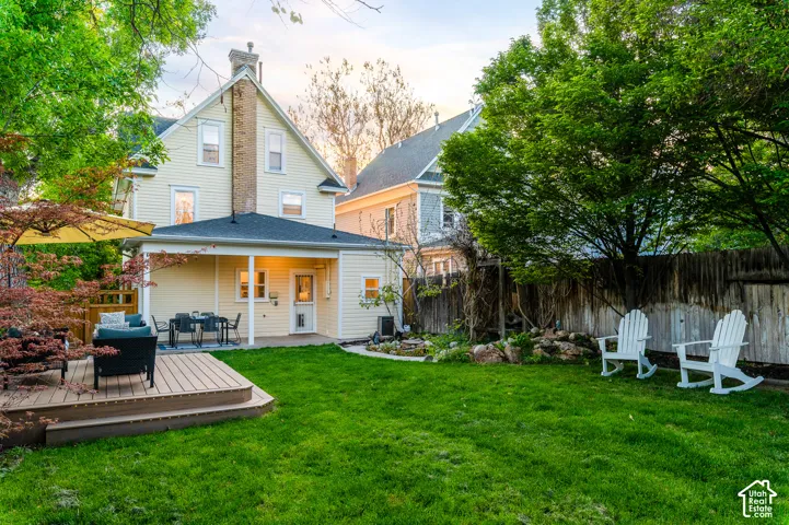 Spacious backyard featuring a manicured lawn, multi-level wood-finish decking, and a covered patio area