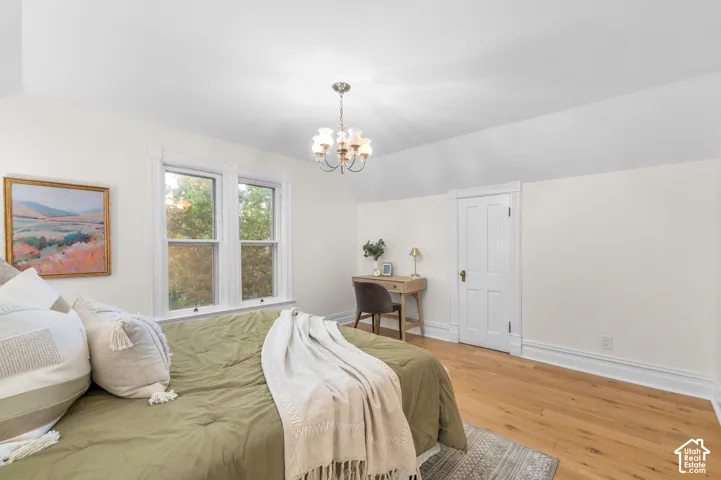 Wood-finish flooring, white trim, dual windows, and a chandelier
