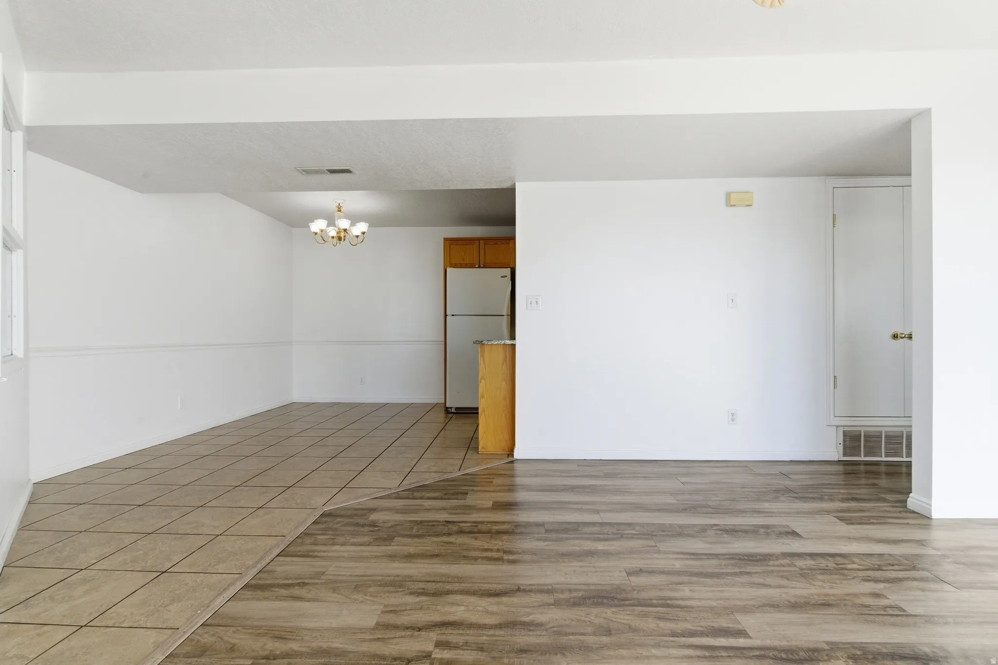 Open-concept living area with wood-finish flooring transitioning to tile