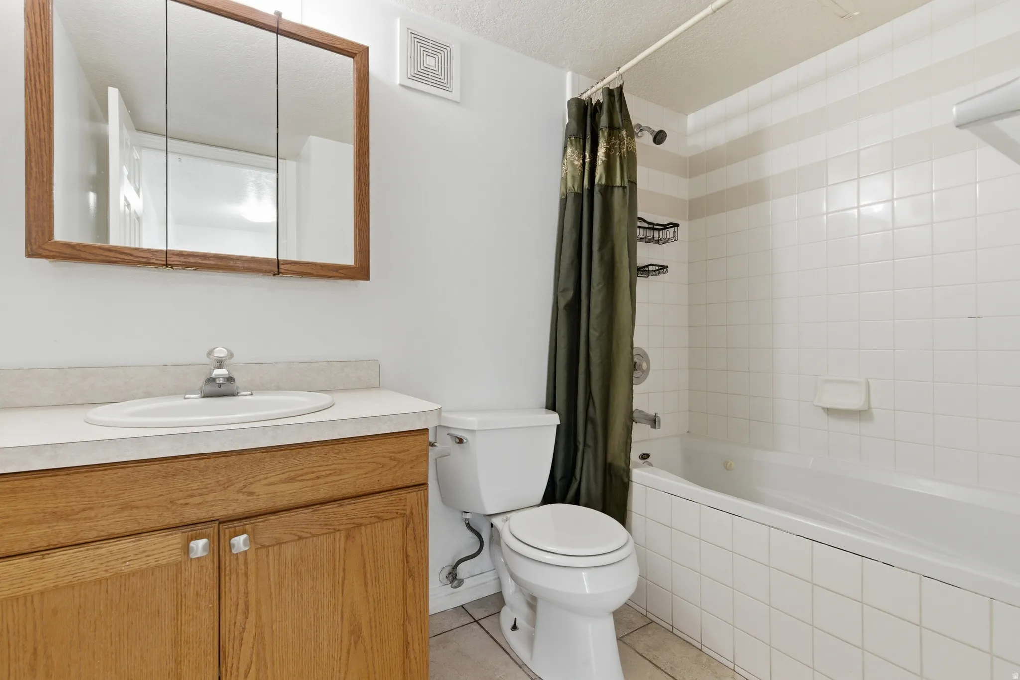 Full bathroom featuring a wood-finish vanity with a laminate countertop, white oval sink, and chrome faucet