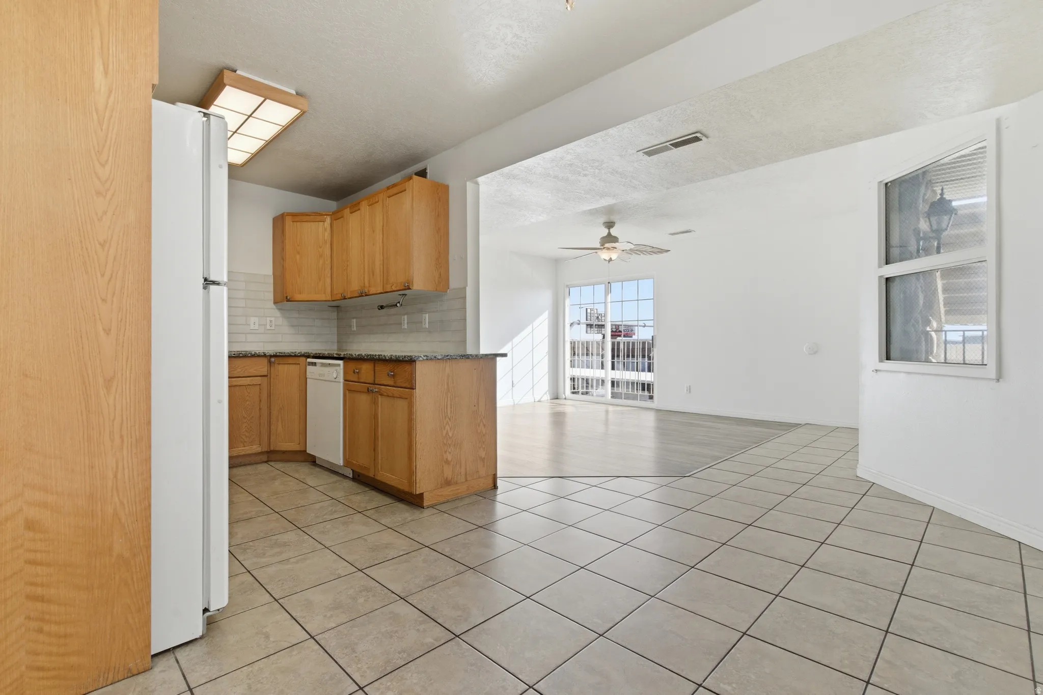 Kitchen featuring wood cabinetry, granite-style countertops, and a white subway tile backsplash