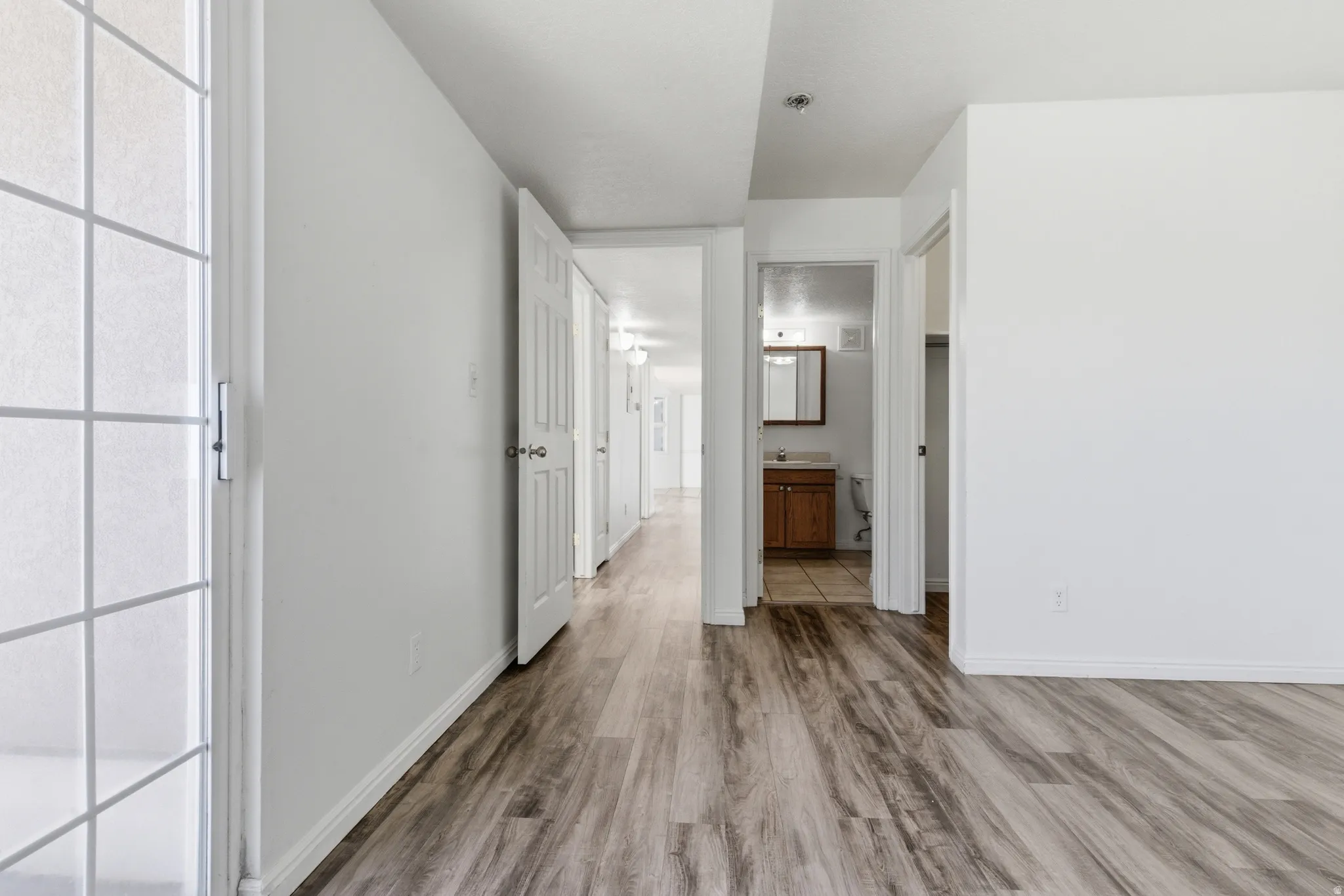 Spacious interior featuring wood-finish flooring, white baseboards, and white walls