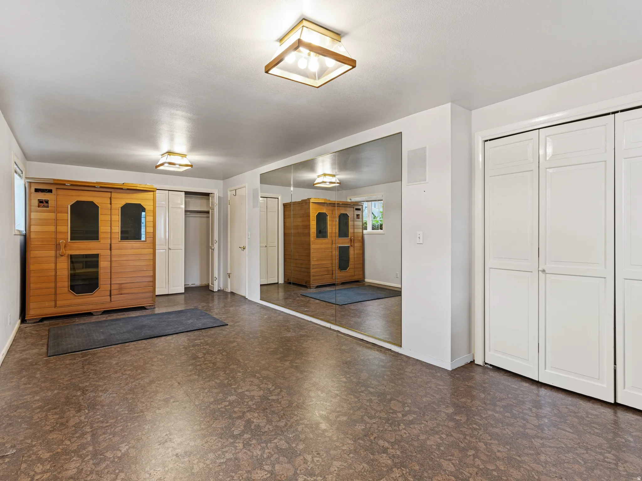 Recreation room with full-wall mirror, two sets of bi-fold closet doors, and recessed lighting