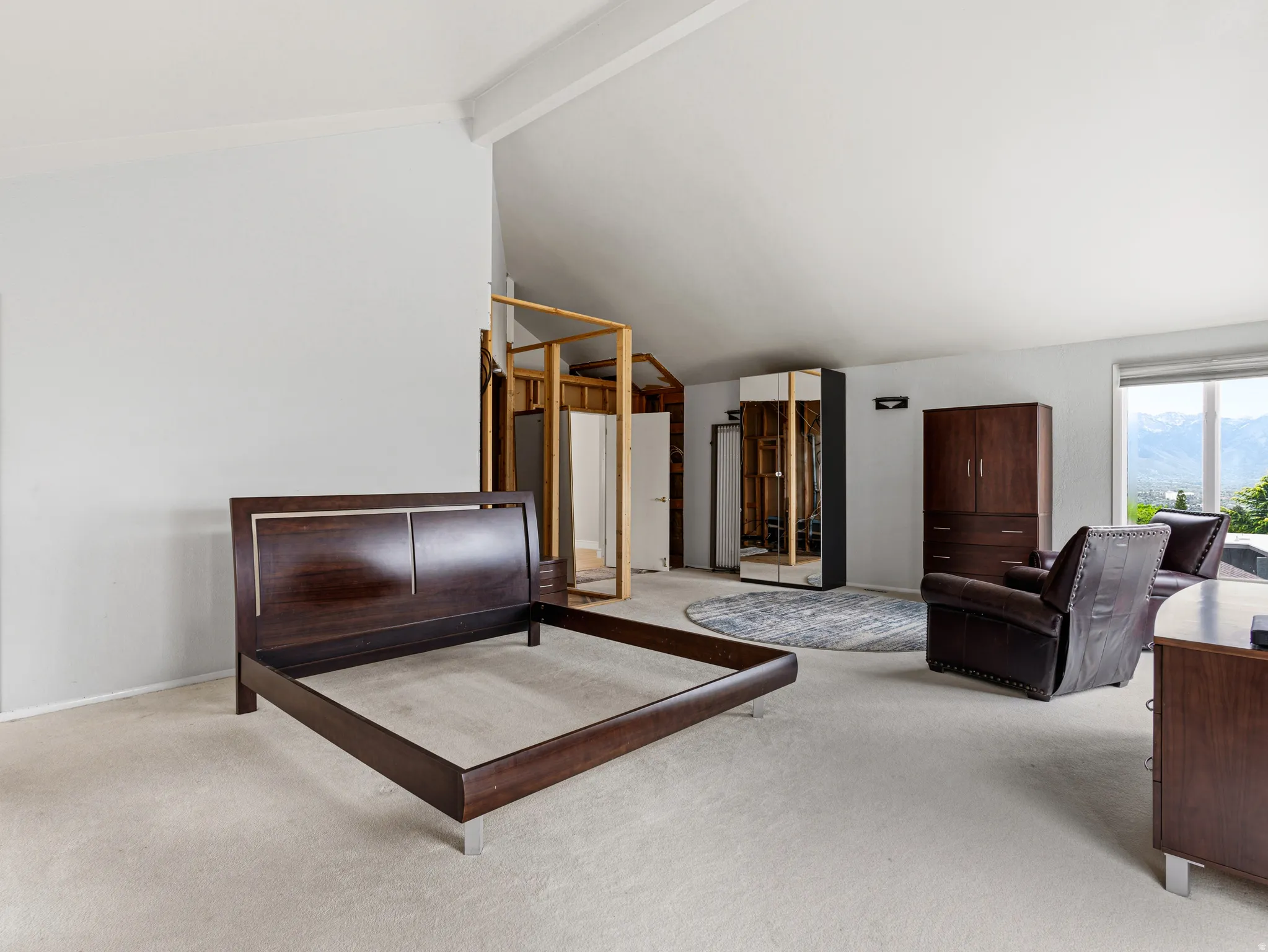 Spacious room featuring vaulted ceilings and light-toned carpeting