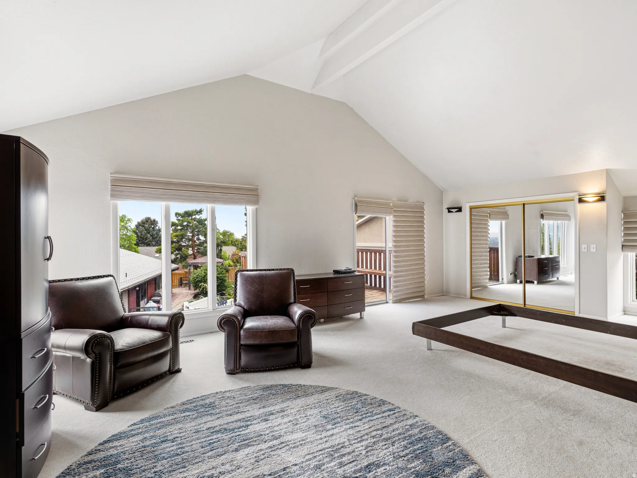 Vaulted ceilings highlight this expansive room featuring carpet flooring