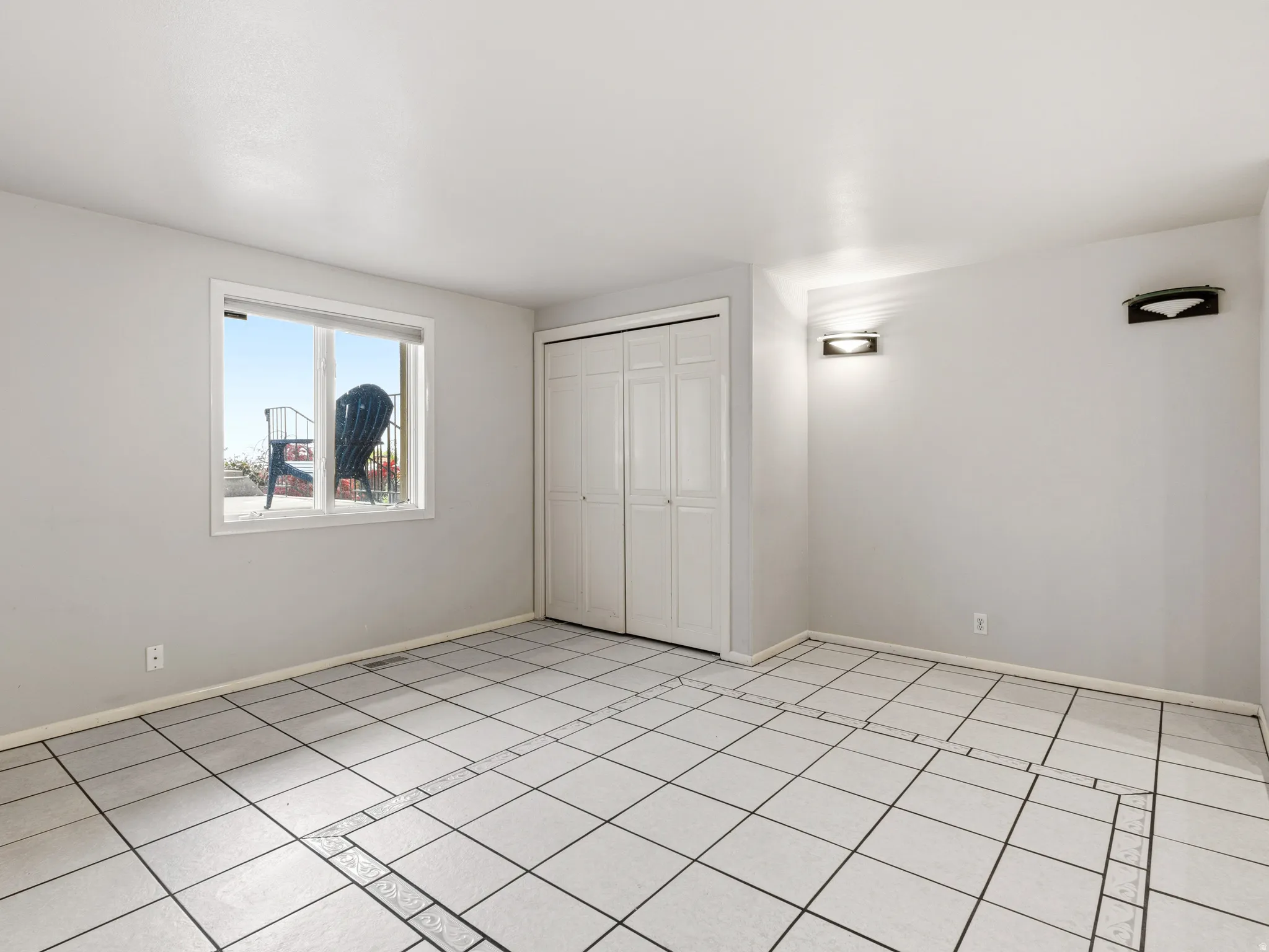 Light gray wall paint, a double window with white trim, and white bi-fold closet doors
