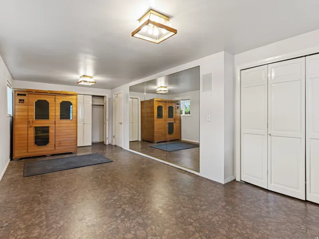 Recreation room with full-wall mirror, two sets of bi-fold closet doors, and recessed lighting