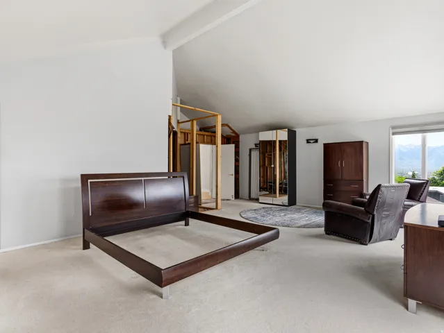 Spacious room featuring vaulted ceilings and light-toned carpeting