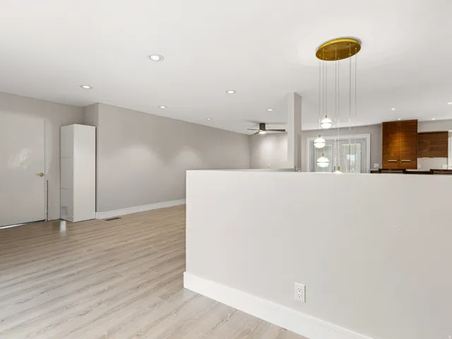 Open-concept living area with wood-finish flooring, recessed lighting, and a modern multi-pendant chandelier