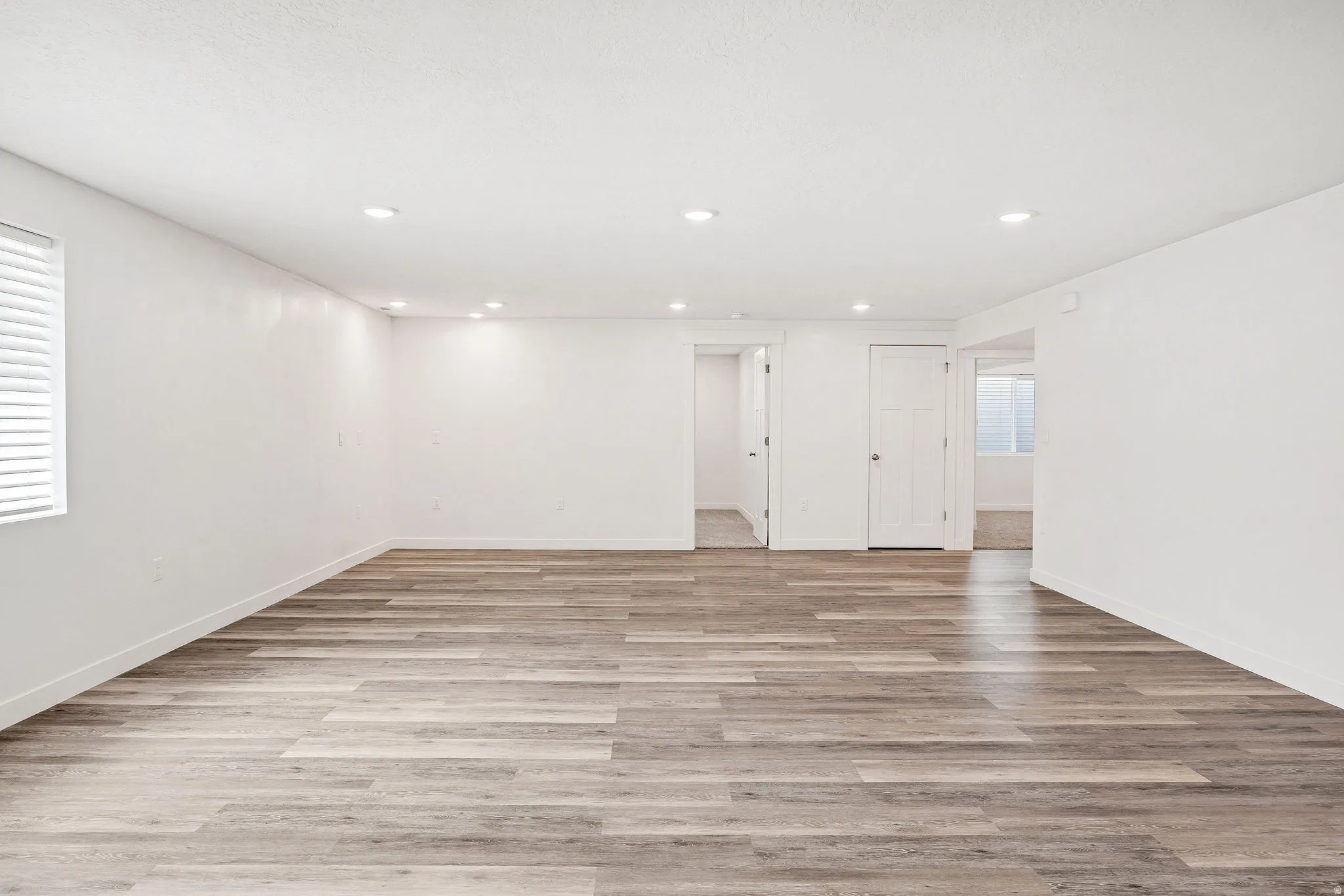 Spacious room featuring wood-finish flooring, recessed lighting, and white walls