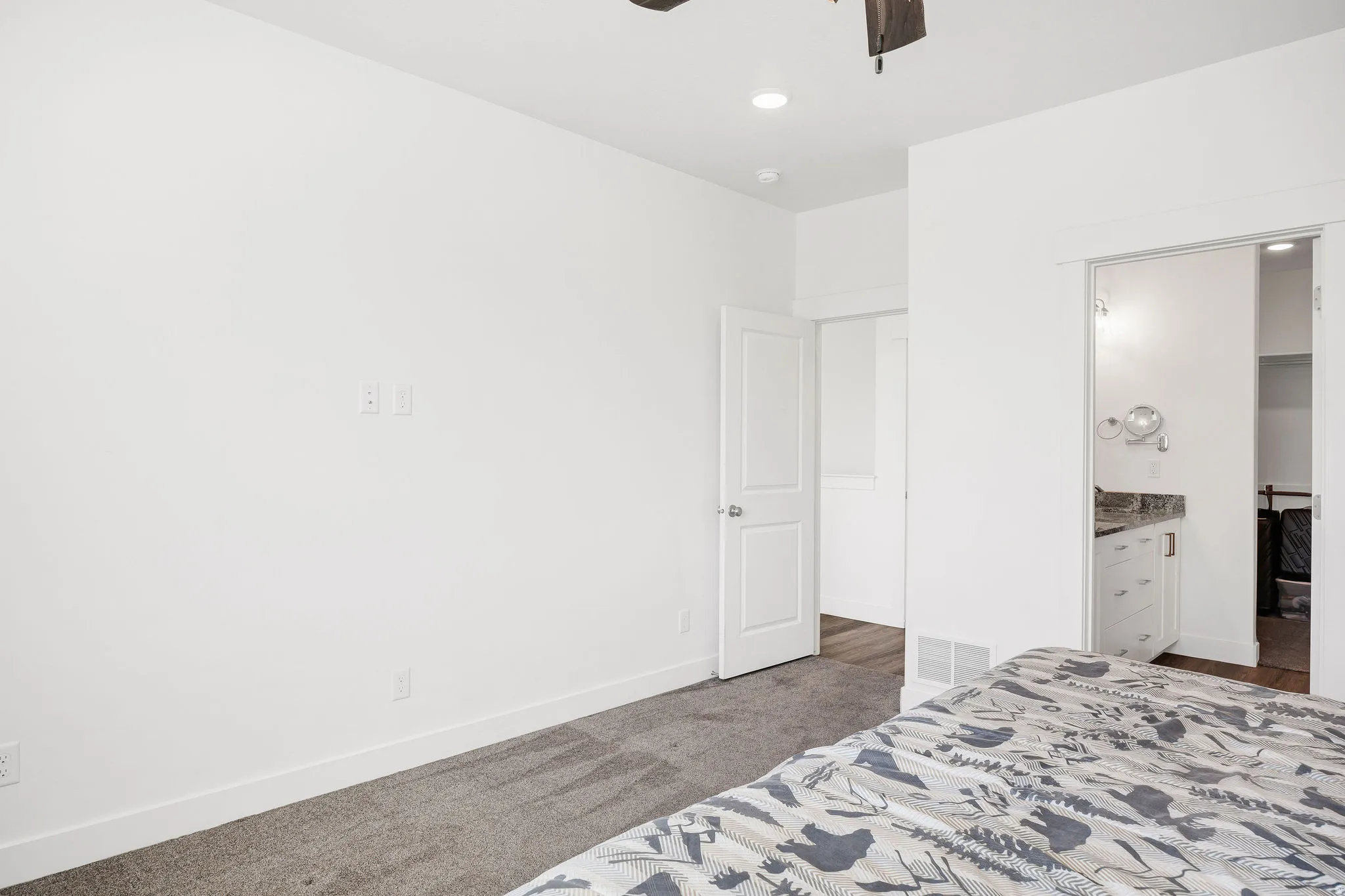 Bedroom with neutral carpeting, white walls, and a ceiling fan