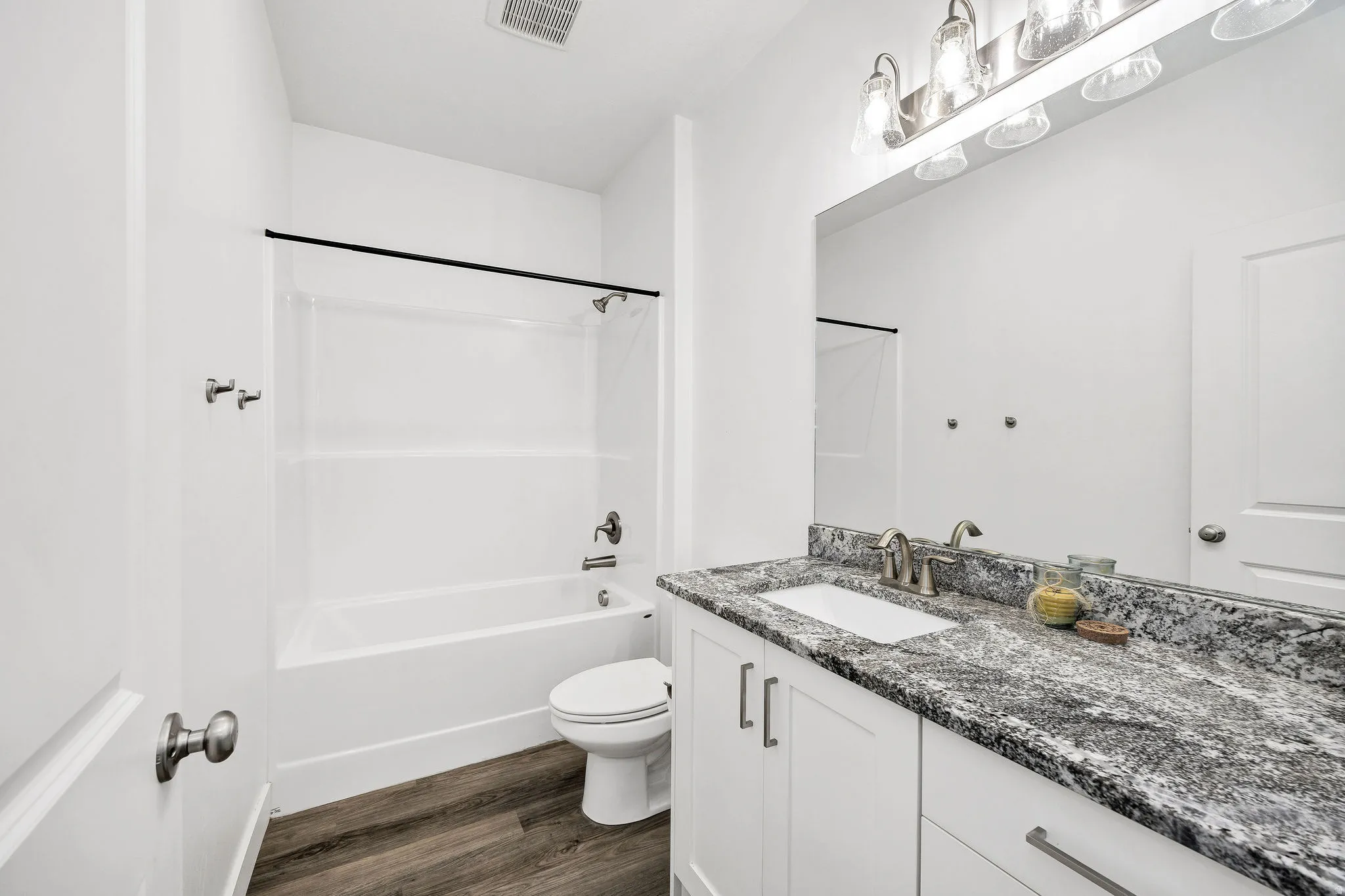 Bathroom featuring a white vanity with a dark speckled countertop, undermount sink, and brushed nickel faucet