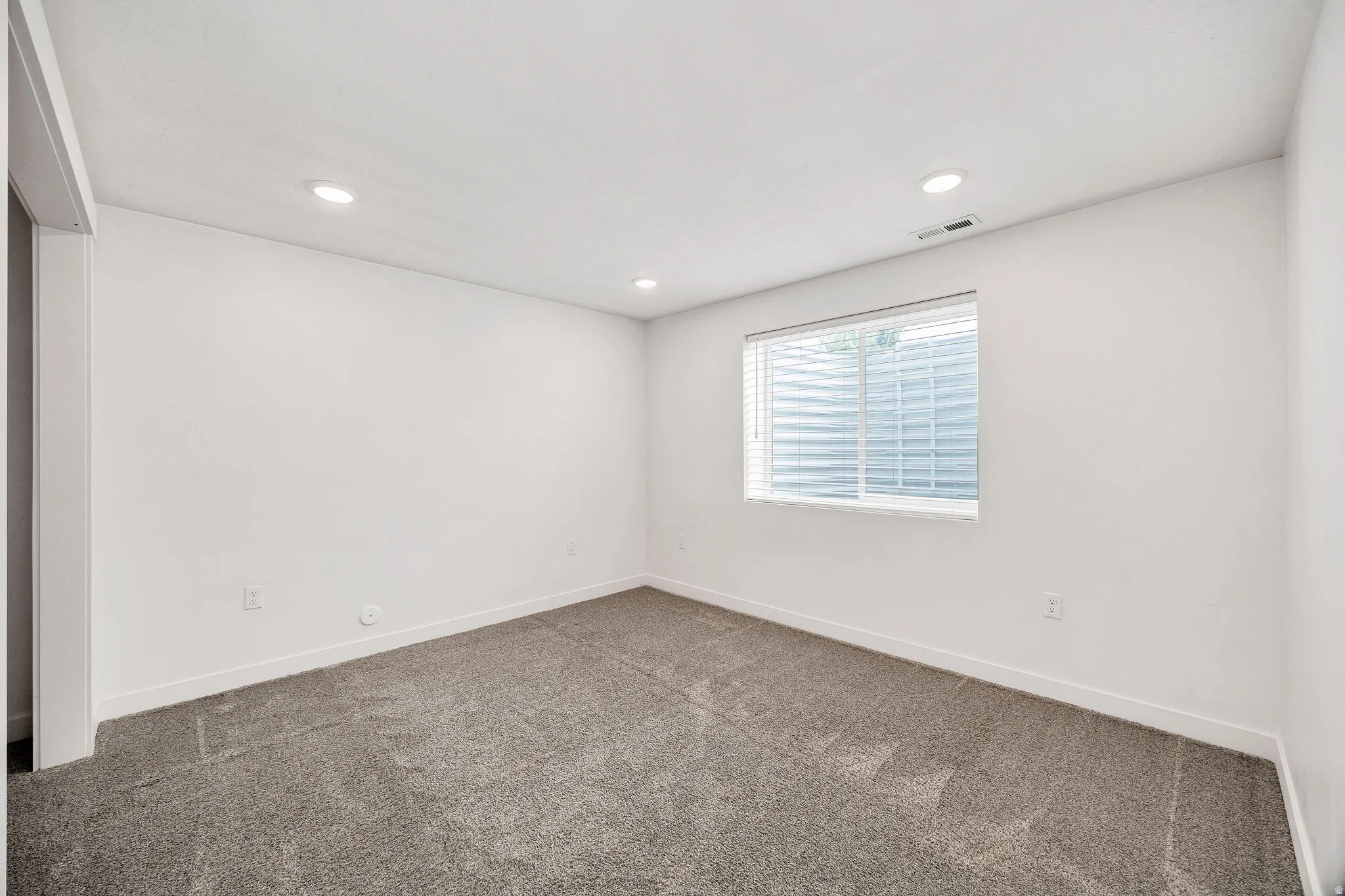 Room featuring recessed lighting, a neutral color palette, grey carpet flooring, white baseboards, and a window with blinds