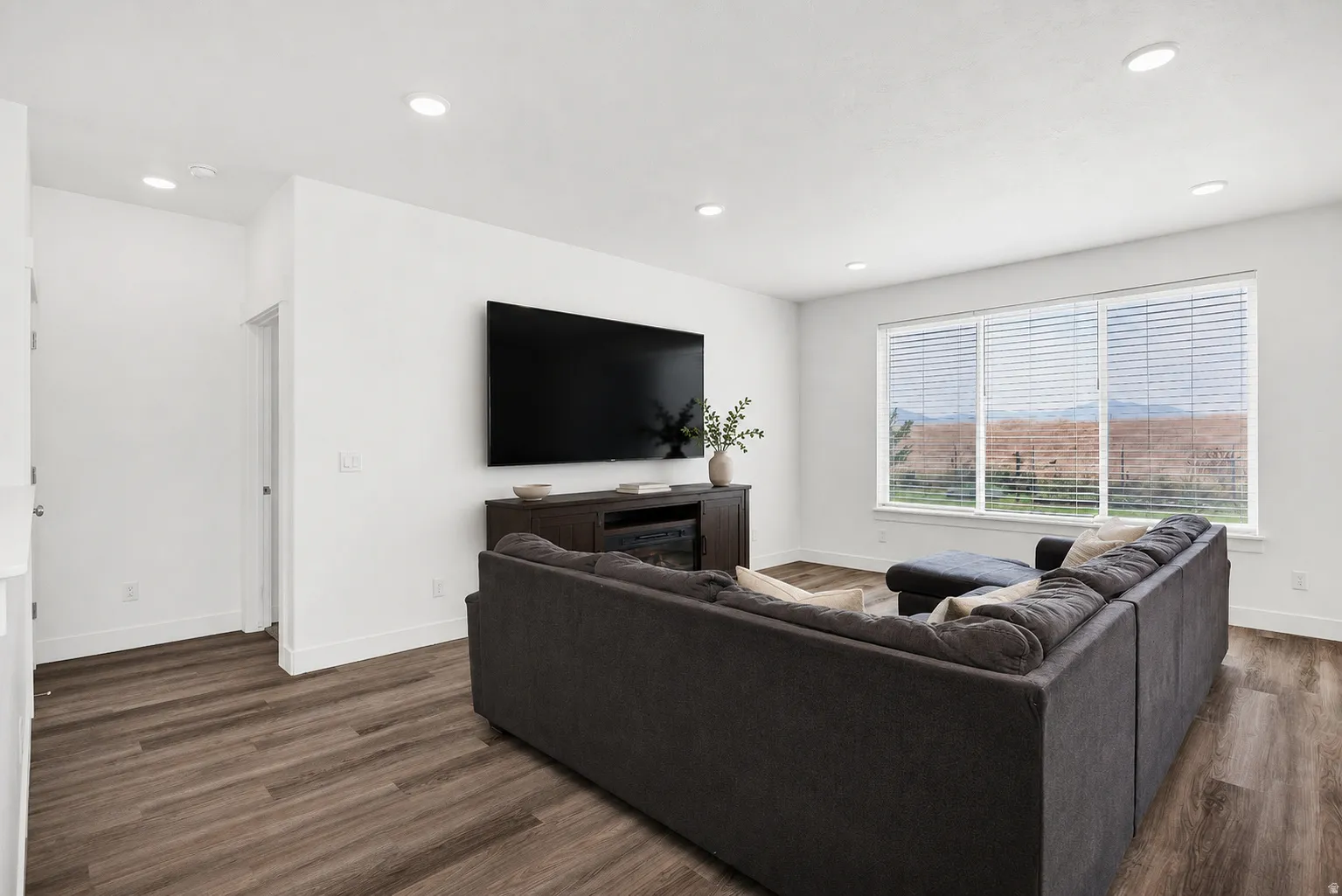 Living area featuring wood-finish flooring, recessed lighting, and white walls