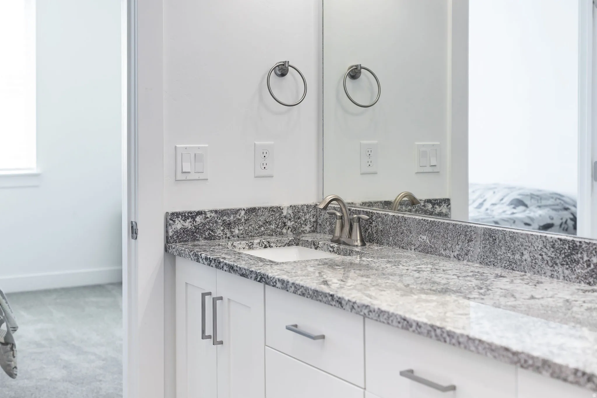Vanity featuring a patterned stone countertop, integrated rectangular sink, and brushed nickel faucet