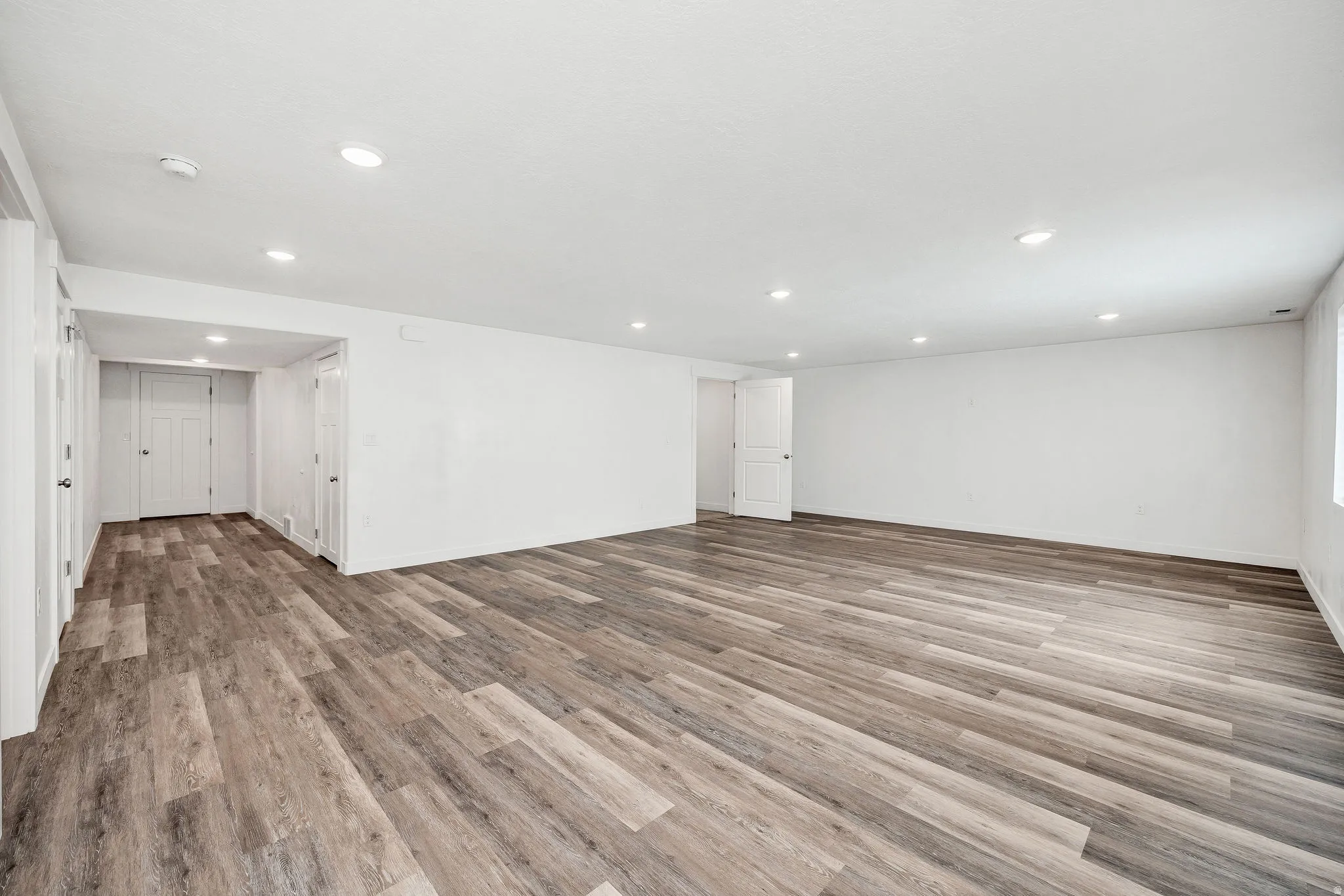 Spacious room featuring wood-finish flooring, recessed lighting, and white walls