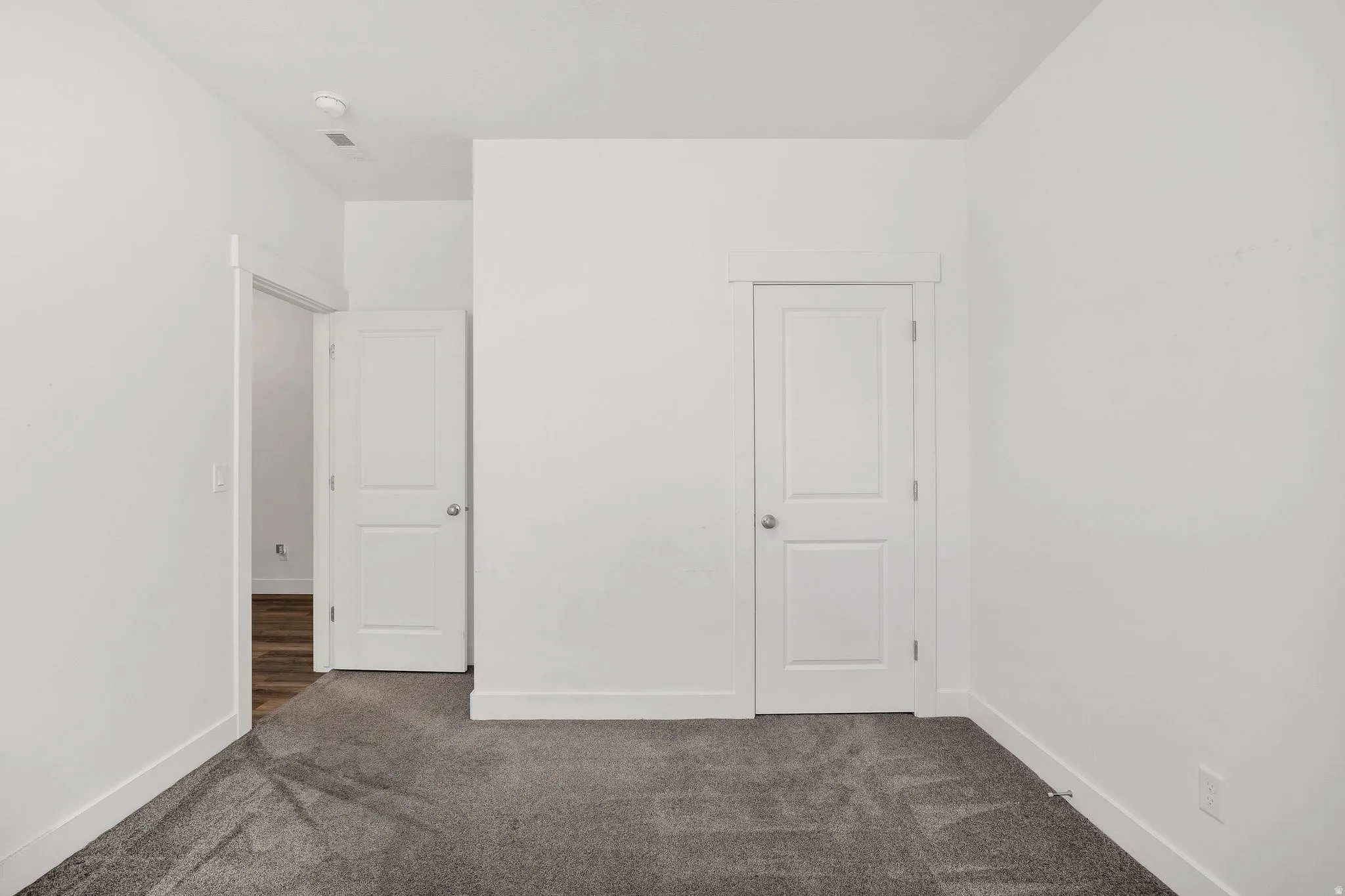 Wall-to-wall carpeting in a neutral tone, crisp white walls, and bright white trim