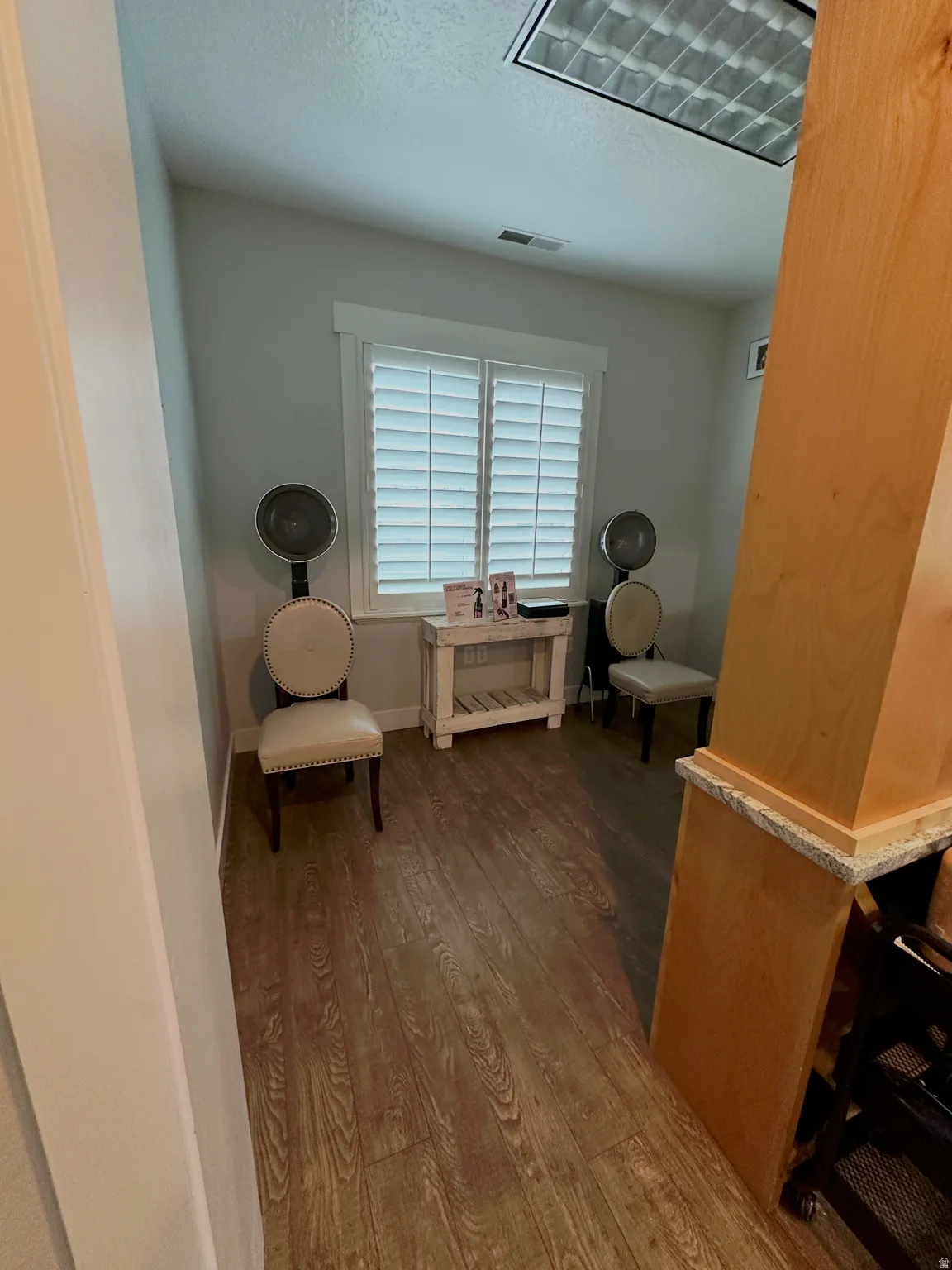 Room featuring wood-finish flooring, white plantation shutters, light gray wall paint, and a built-in light fixture