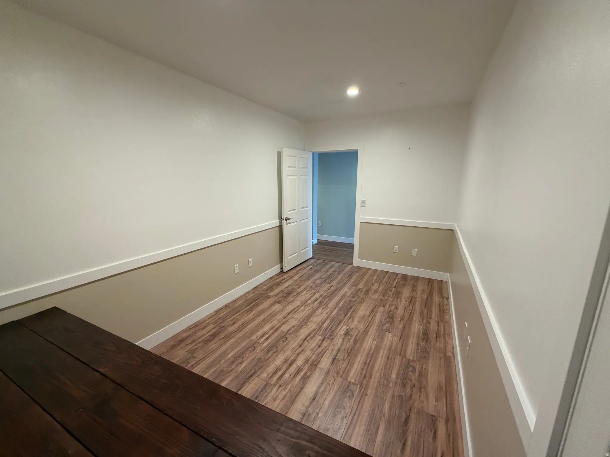 Room featuring wood-finish flooring, two-tone wall paint with chair rail molding, and a recessed ceiling light