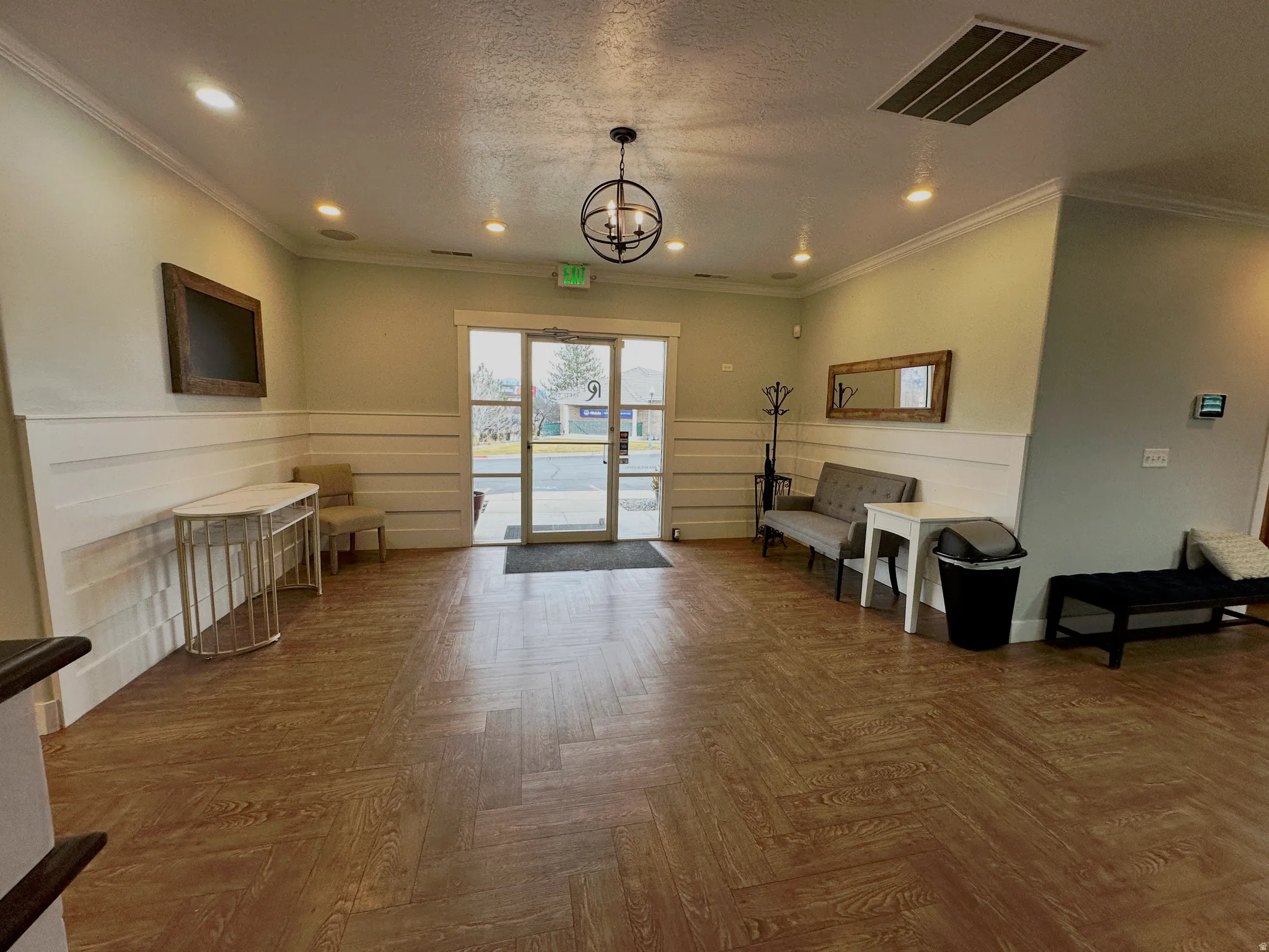 Spacious entry area featuring wood-finish flooring in a herringbone pattern, wainscoting, crown molding, and recessed lighting