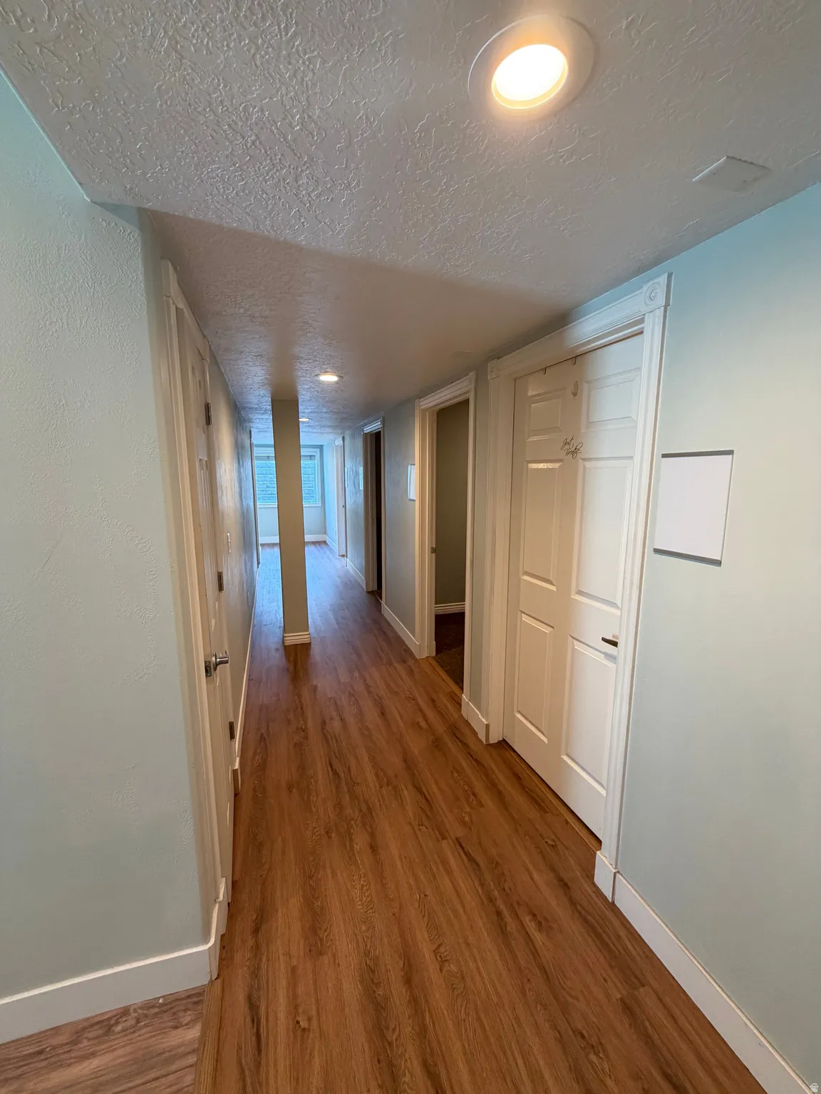 Hallway featuring wood-finish flooring, recessed lighting, light-toned walls, and white trim