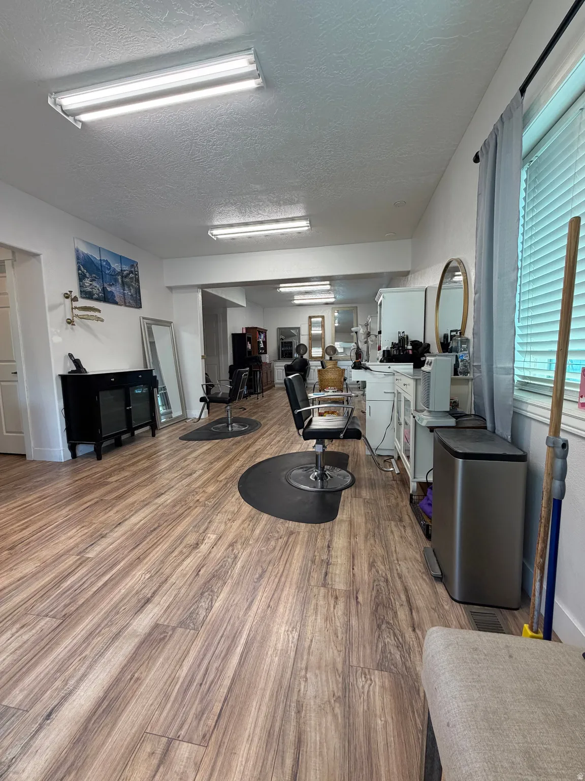 Spacious interior featuring wood-finish flooring, multiple recessed lighting fixtures, and abundant natural light from a window with blinds