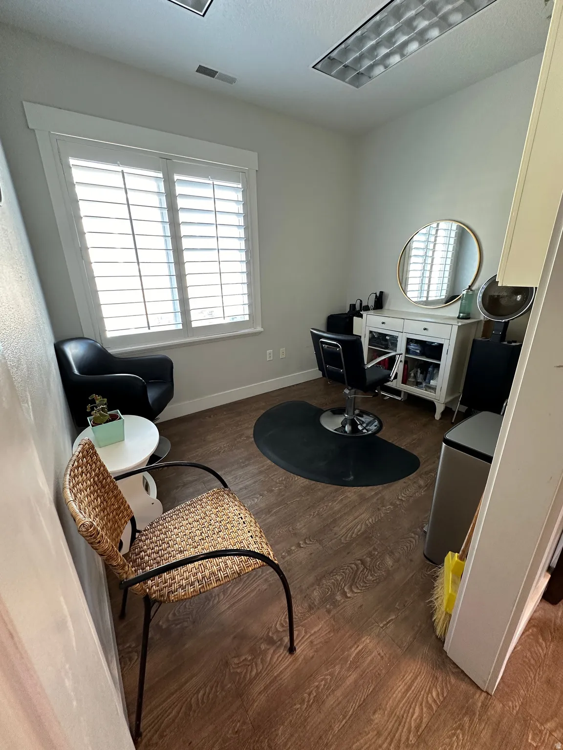 Room featuring wood-finish flooring, white plantation shutters, and recessed fluorescent lighting